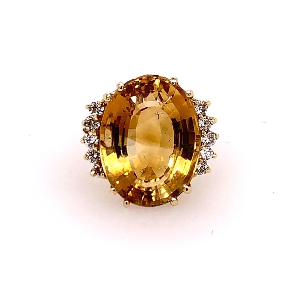 A Magnificent Natural Oval Citrine Quartz Cocktail Ring (size 6). 

Set in 14k Yellow Gold, the centerstone measures APPROXIMATELY 18.50x14x10.5mm and weighs APPROXIMATELY16.50 Carats. Set beside the Oval are ten colorless natural round brilliant