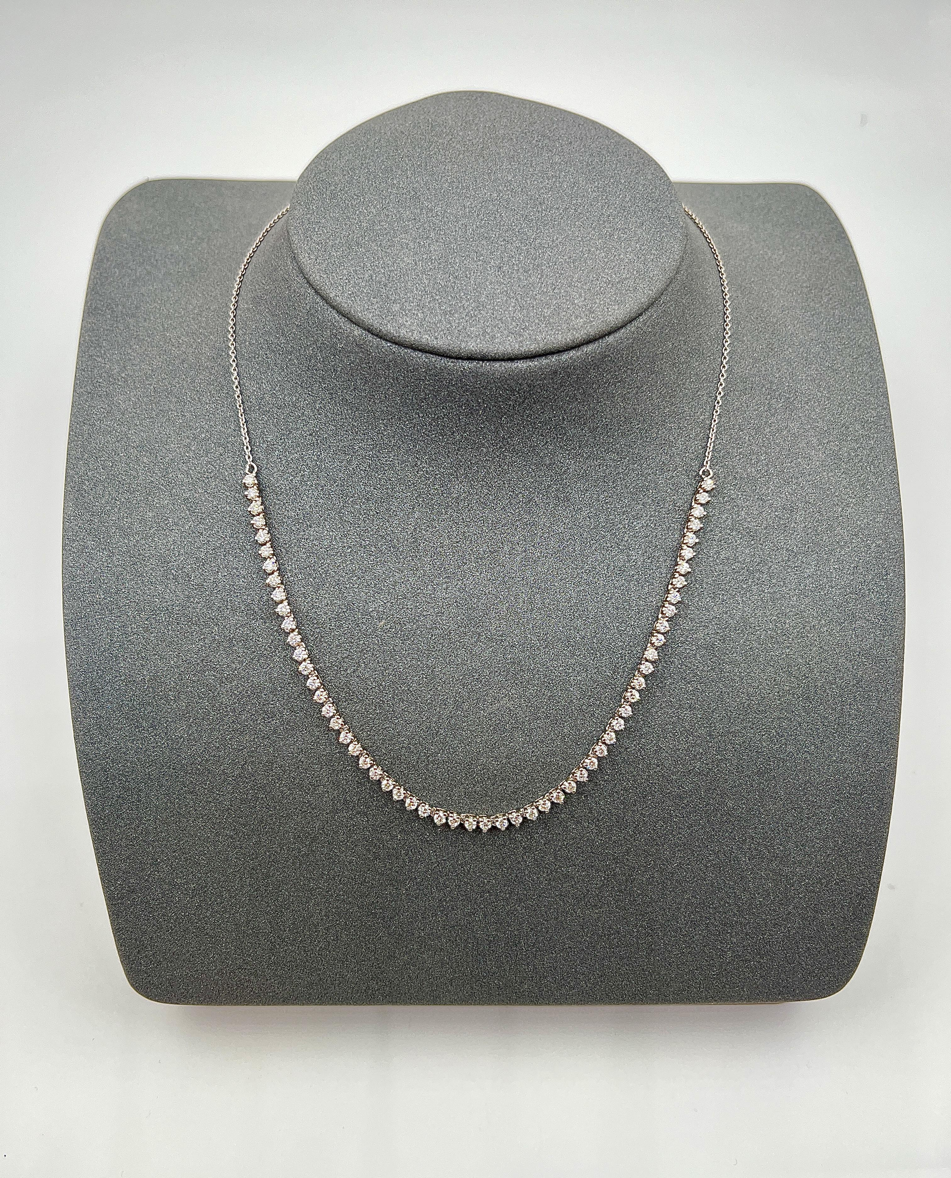 This elegant necklace is a timeless and versatile piece that is perfect for any occasion. It features a series of round diamonds set in a 14k white gold bezel. The diamonds are of G/H in color and VS2/SI1 clarity, and each has a white hue. The