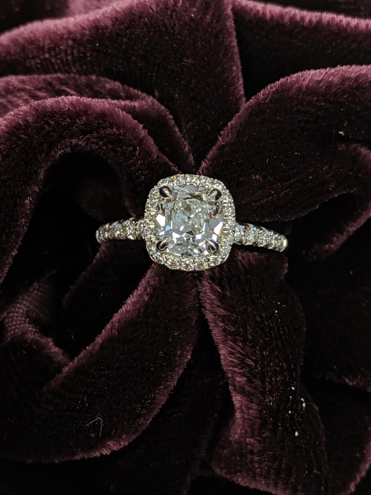 This exquisitely made cushion cut diamond ring features a center 1.27 carat F color VS2 clarity cushion cut diamond as graded by GIA (Report Number
2155232153)  It is set in a halo of smaller diamonds and platinum and is located in our Diamond