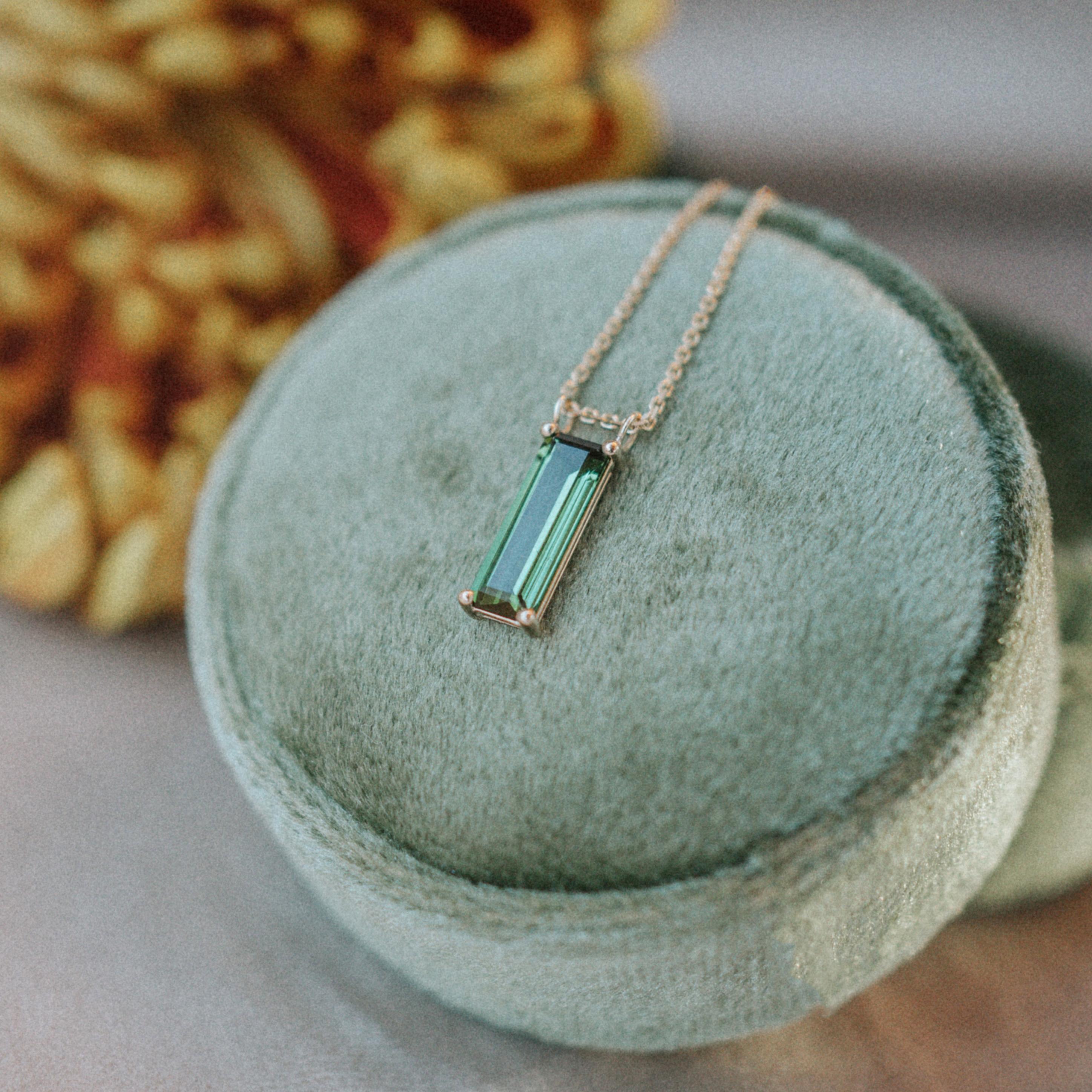 Necklace with a natural green tourmaline set in yellow gold 14k.
Tourmaline of 1.6 ct, cut as an elongated baguette (13 mm x 4.5 mm) is sliding on the diamond-cut chain 18