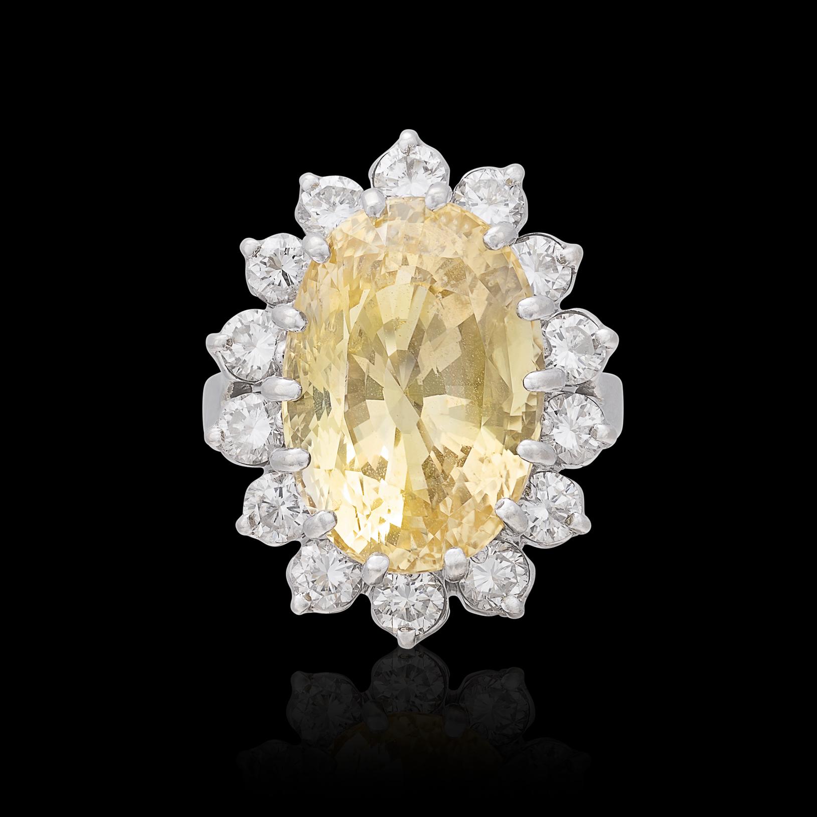 Make a statement with this stunning 14k white gold ring that features a phenomenal yellow sapphire surrounded by a halo of sparking round diamonds. The well-saturated oval yellow sapphire weighs approximately 16 carats and the total diamond weight