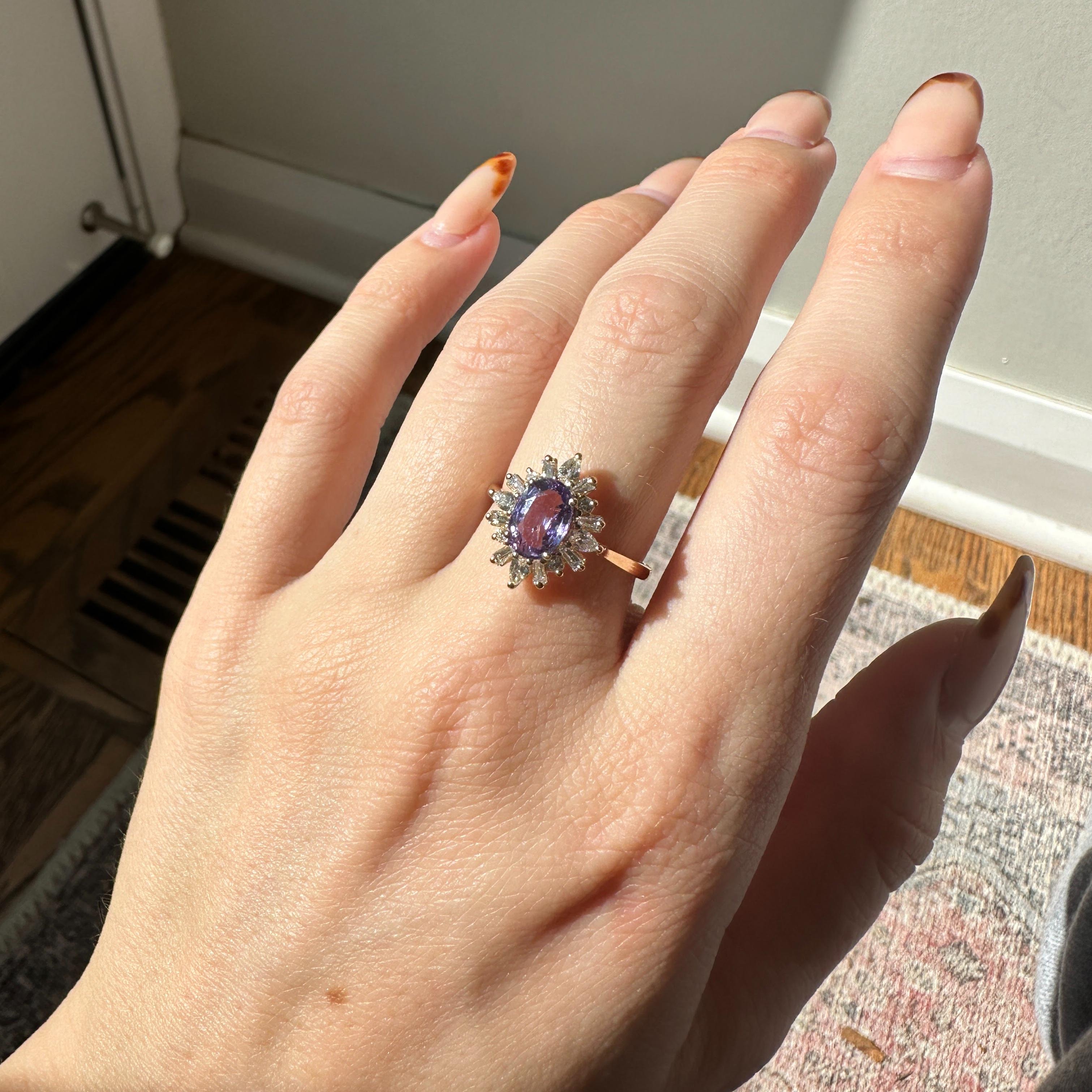 Exquisite and striking, this ring features a 1.65 carat oval Purple Sapphire gemstone surrounded by a radiant halo of natural earth mined diamonds set in solid 14K gold. Ideal for any occasion, this piece is both eye-catching and elegant. This