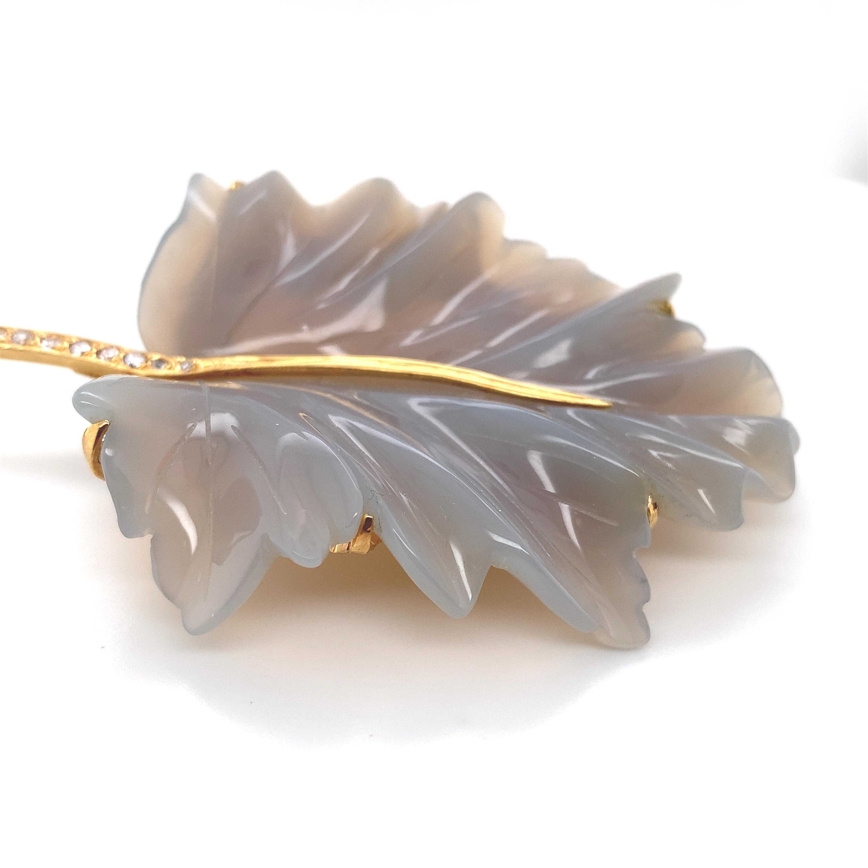 16K yellow gold pin featuring a finely carved slightly bluish-grey chalcedony leaf. The pin is handmade, signed S&CJ WES and marked .666 which is 16K gold. The carved stone leaf is very large measuring 2 3/8