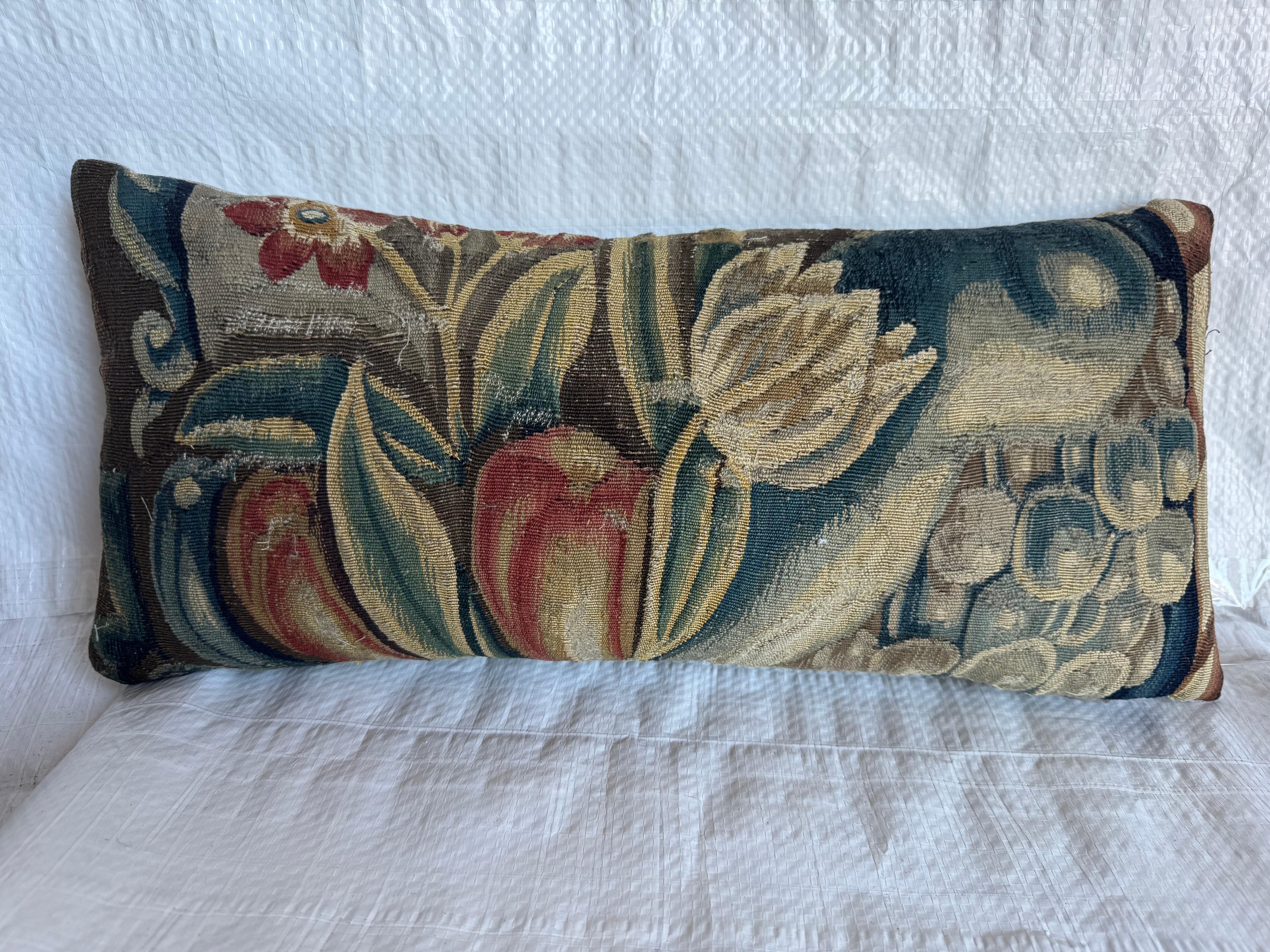 Un vibrant fragment de tapisserie bruxelloise du XVIe siècle présentant des fleurs stylisées, des fruits et des feuillages tissés dans une palette magnifiquement vieillie d'indigo profond, de sarcelle sourde, de blé doré, de vert d'olive, de rouge