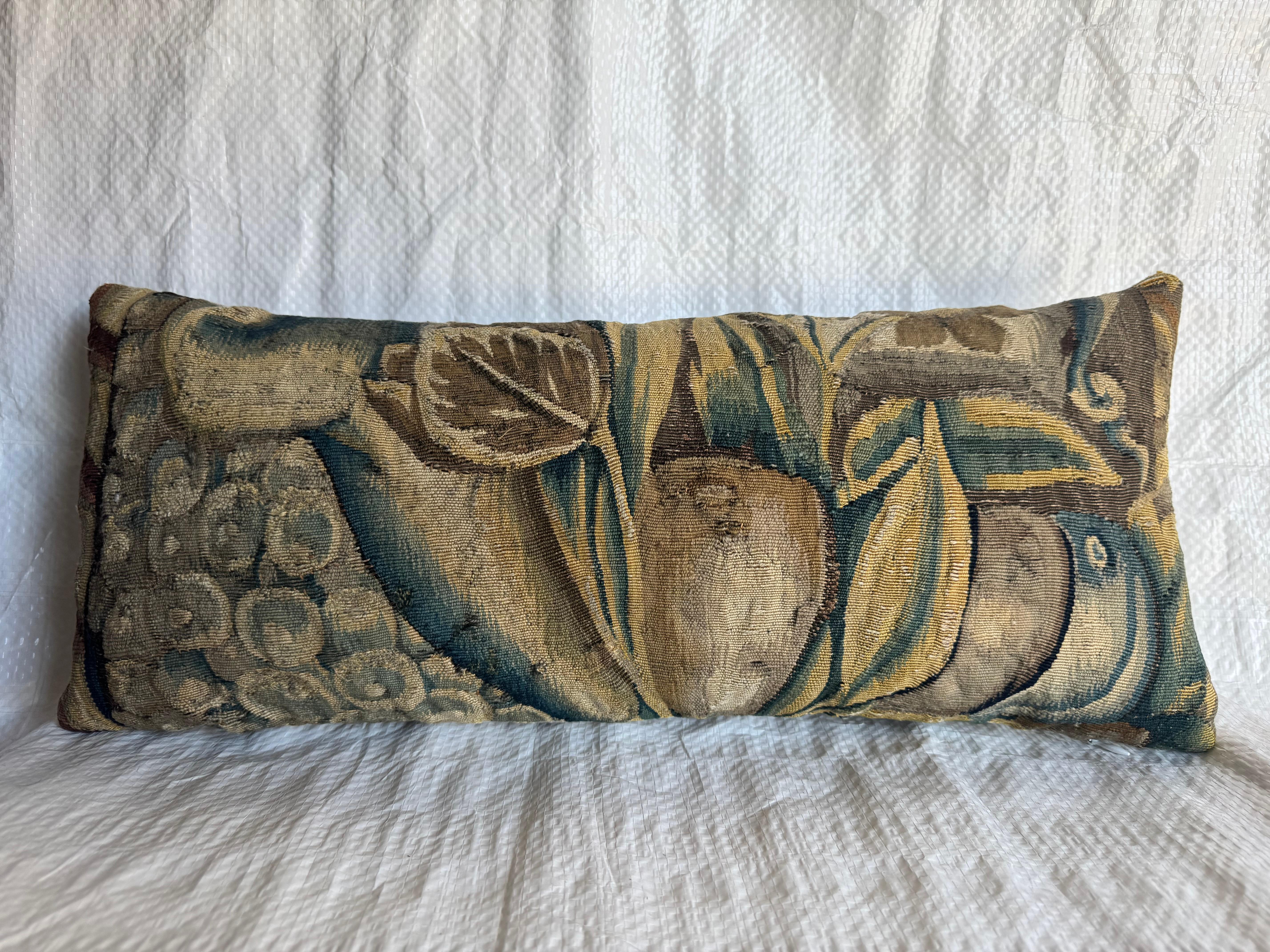 An exceptional pillow crafted from a 16th-century Brussels tapestry fragment, woven in wool and silk with masterful shading and depth. The design features lush Baroque foliage intertwined with fruit and scroll motifs, emblematic of the opulent