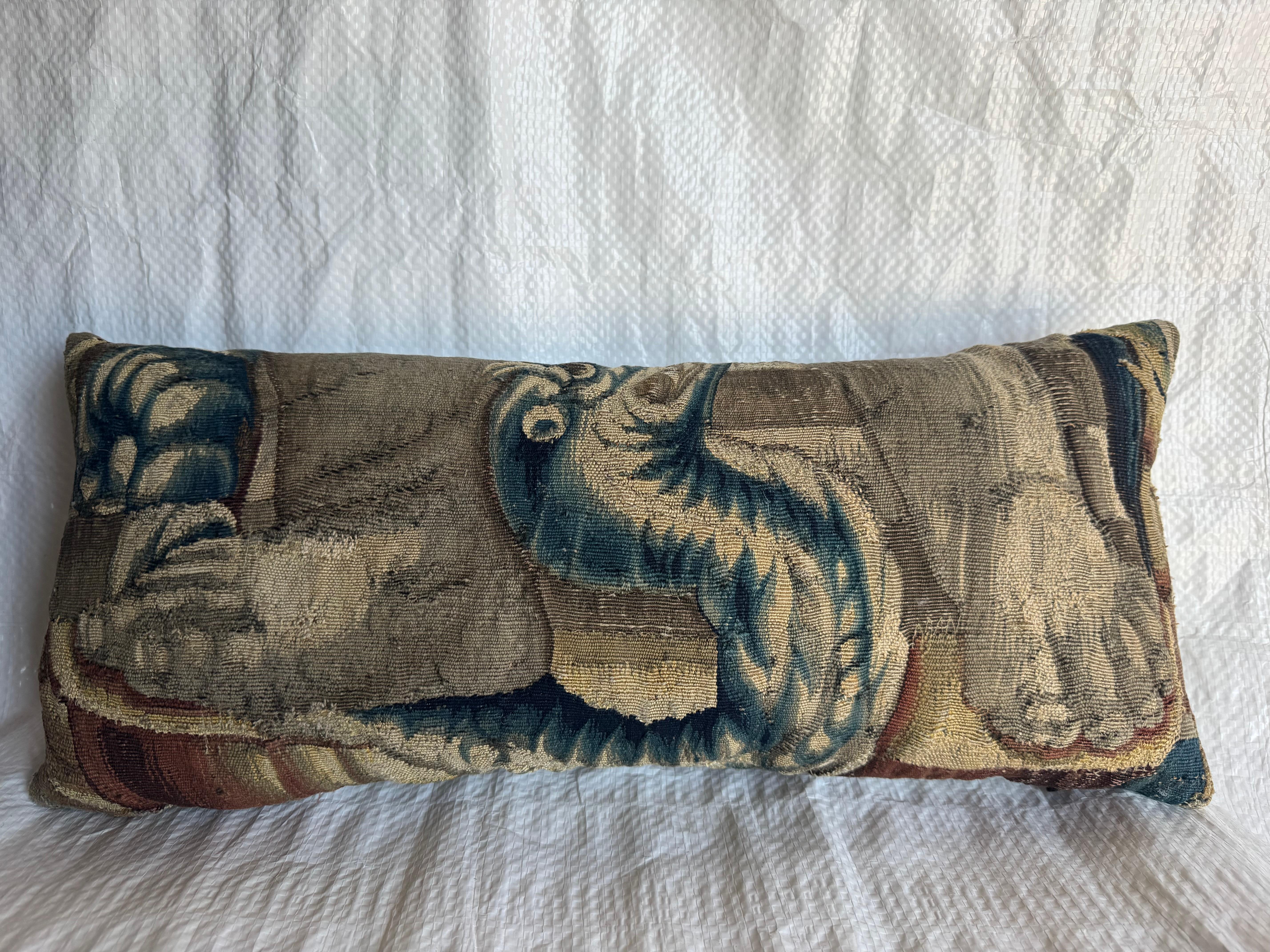 A remarkable 16th Century Flemish Brussels tapestry fragment repurposed as a decorative pillow, depicting a lion’s paw and scrolling acanthus leaf—motifs emblematic of Renaissance artistry. Handwoven in wool and silk, this piece exhibits the refined
