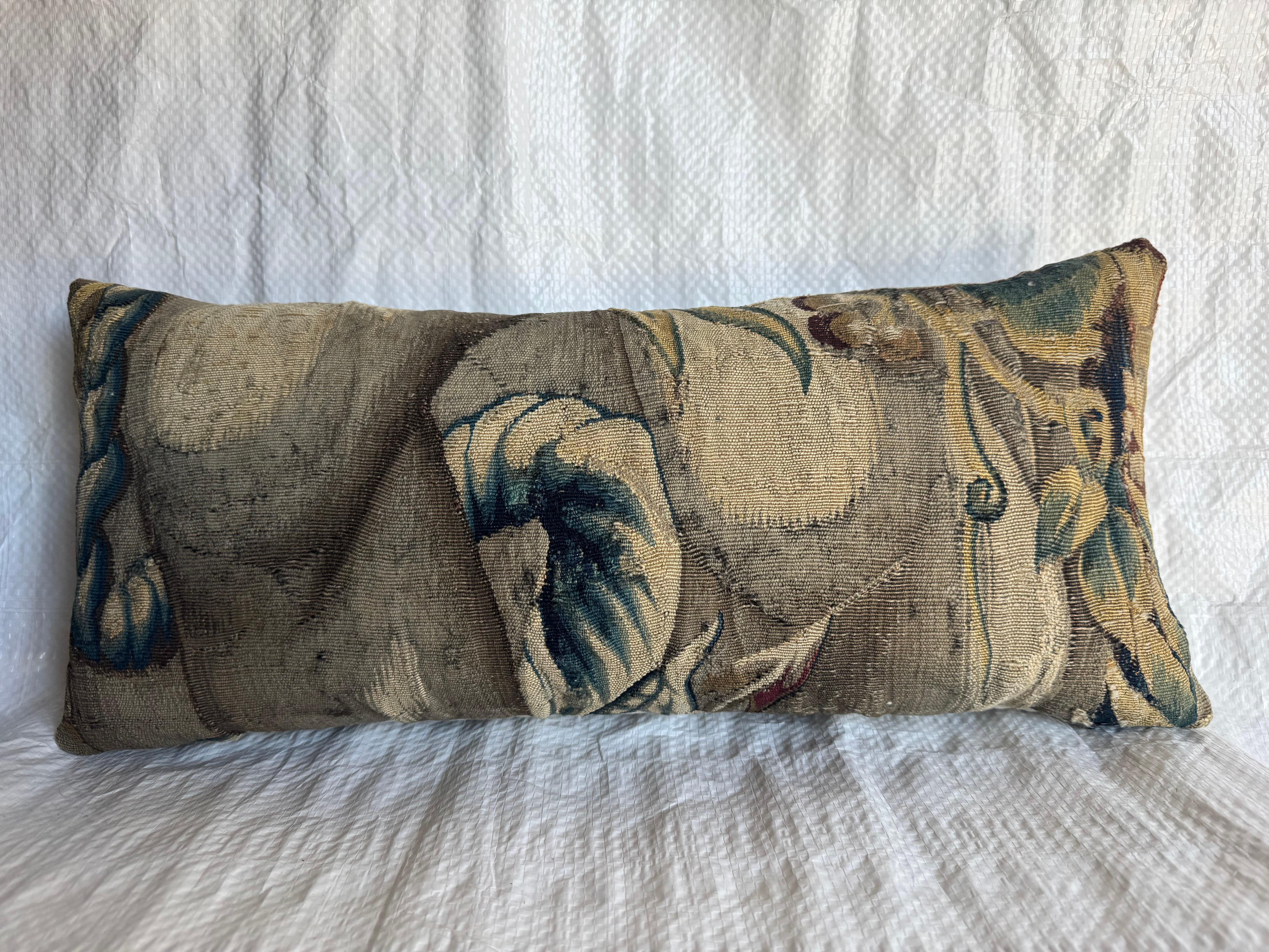 Uno squisito frammento di arazzo di Bruxelles del XVI secolo trasformato in un raffinato cuscino decorativo. Tessuto in lana e seta, questo pezzo presenta un classico fogliame barocco con morbide tonalità blu-verdi e dorate, caratteristiche