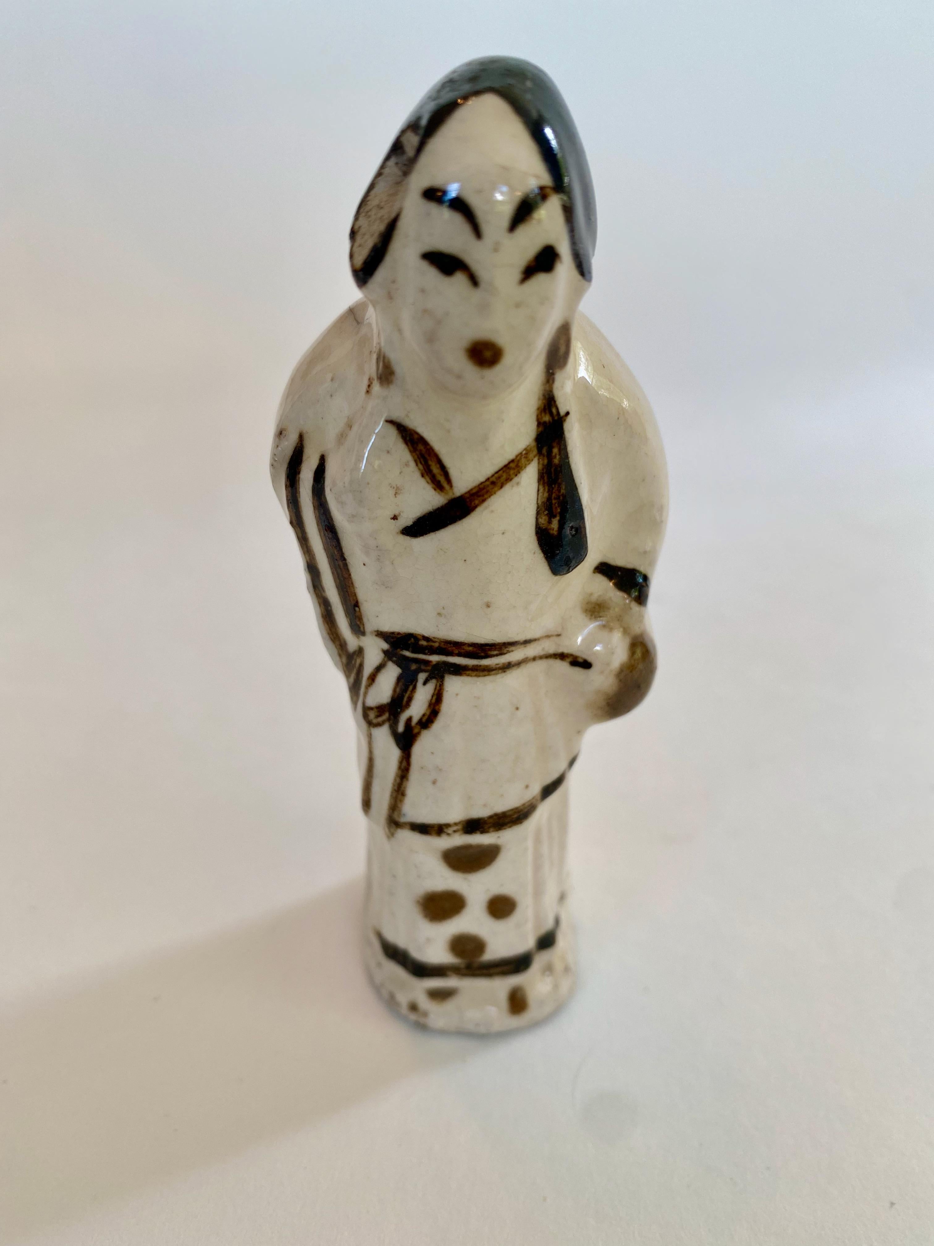 Ming dynasty pottery figure of a standing woman, likely from the Suzhou region.
This is a small figure with a lot of personality, rendered in cream and dark brown. WIth her slightly hunched stance and her hands in the folds of her kimono, a whole