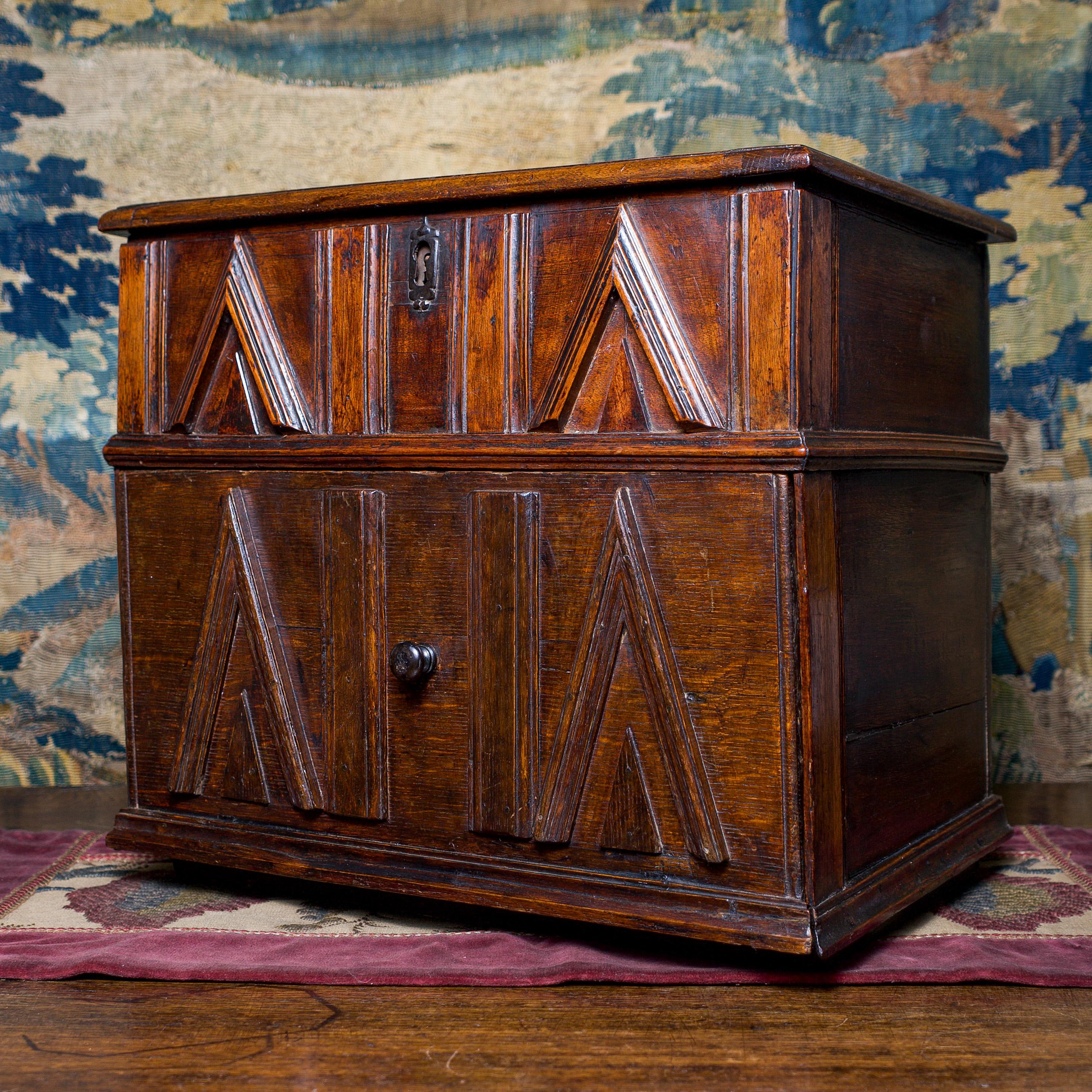 Rare Elizabeth I oak, walnut & chestnut table cabinet, with a hinged top enclosing a well. Above a frieze of geometric mouldings, the lockable fall-front reveals a configuration of seven internal drawers with secret compartments to the back of the