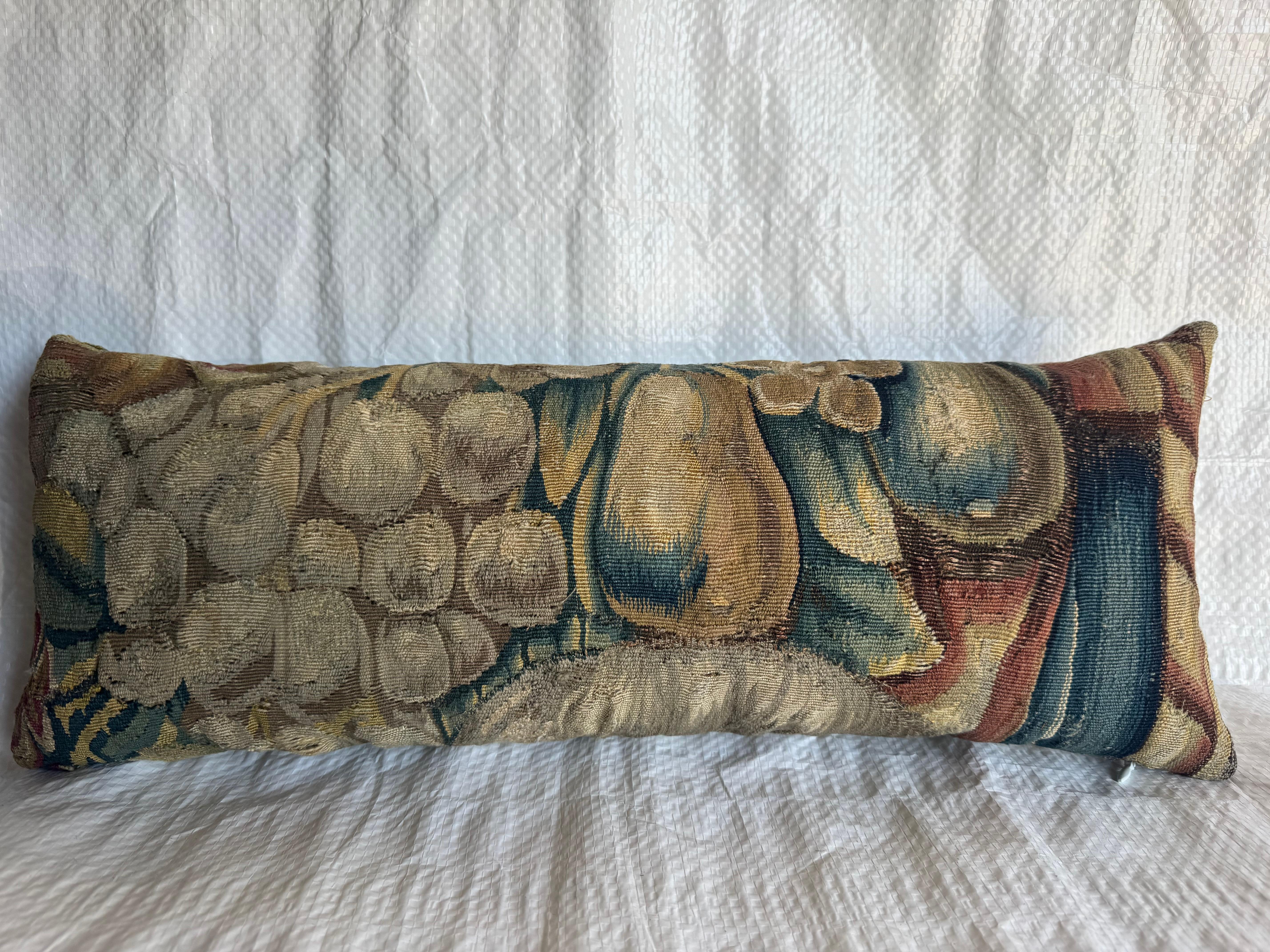 Un superbe exemple de fragment de tapisserie flamande de Bruxelles du XVIe siècle transformé en oreiller décoratif. Le panneau présente une nature morte magistralement tissée de raisins et de fruits sur un fond baroque richement stratifié,