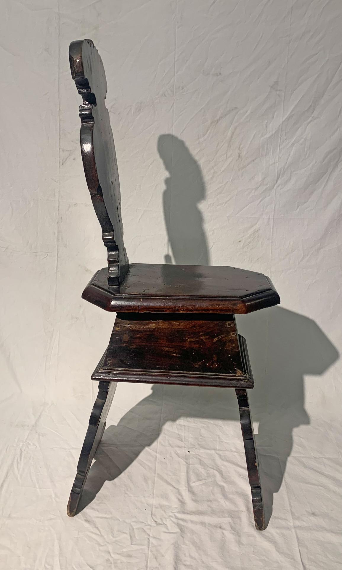 Typical stool with backrest and curved legs in solid walnut wood with dark patina. This type of bench is used in guard posts, for this reason the seat is small and uncomfortable, to prevent the soldier from falling asleep at night. The stool can be
