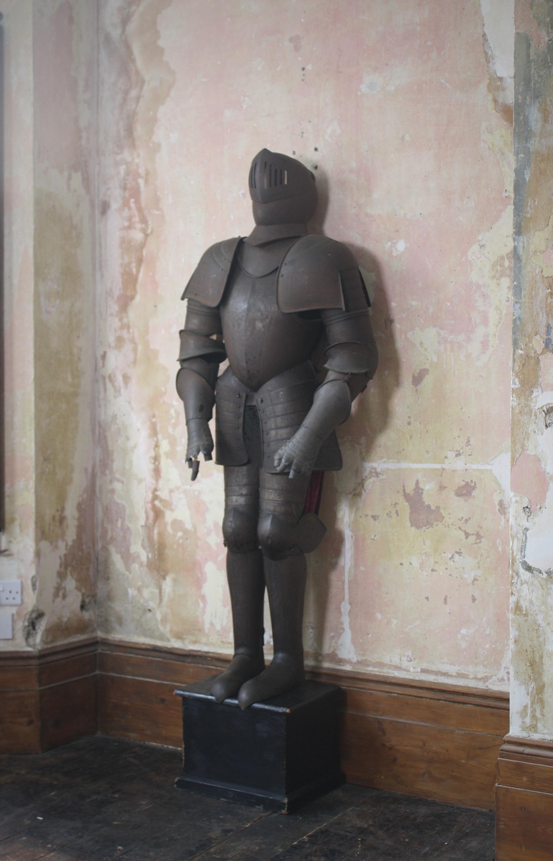 A decorative and imposing country house Victorian suit off armour, in the 16th century style.

Later mounted on a ebonised plinth with internal wooden skeleton for support and velvet vale on the rear. Of riveted construction with fine engraved