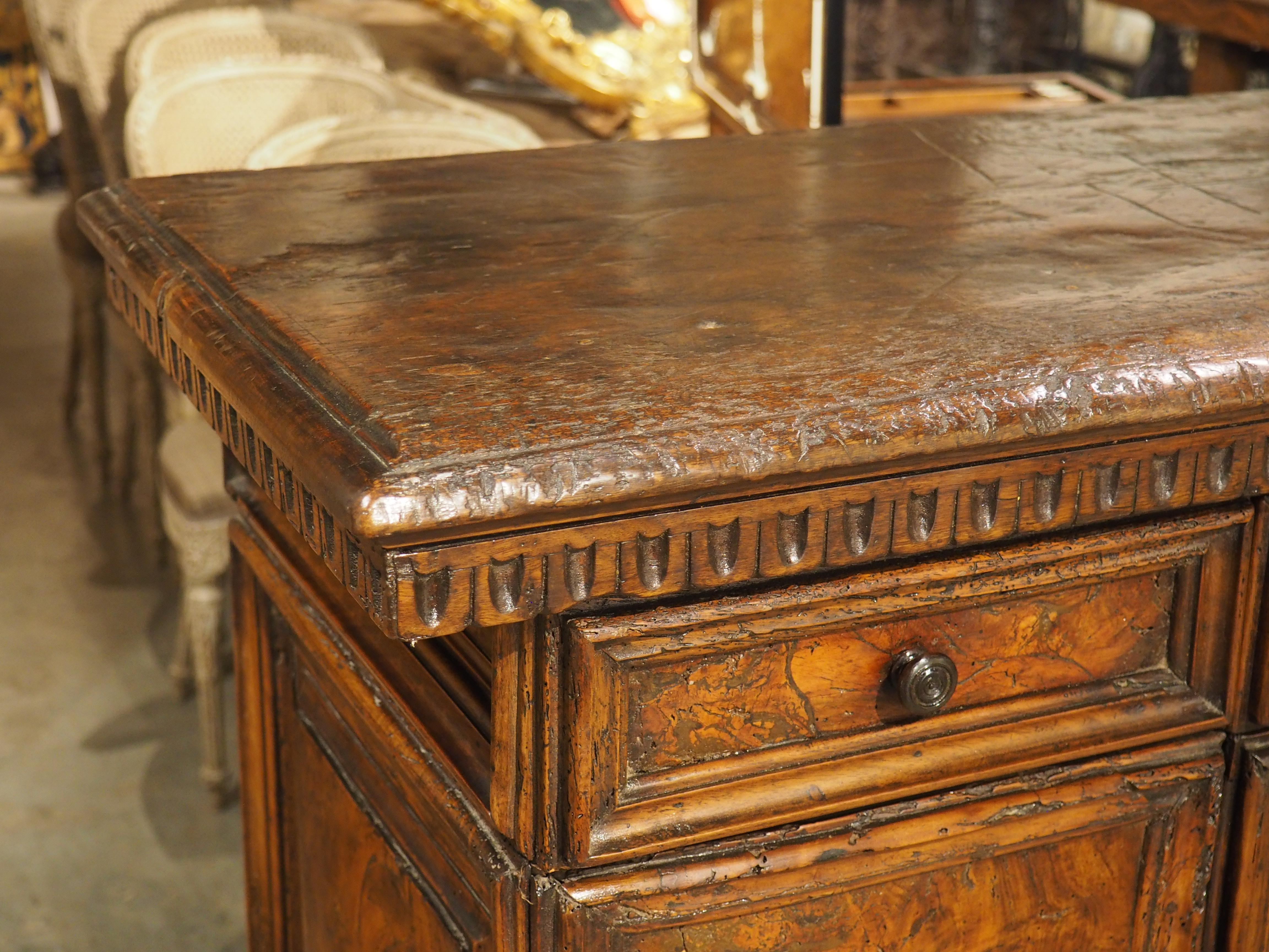 A beautiful piece of Italian furniture, dating to the High Renaissance of the 1500s, this walnut credenza has a fascinating intarsia burr façade. The front, which consists of three belt drawers above a pair of rectangular doors, has burl walnut