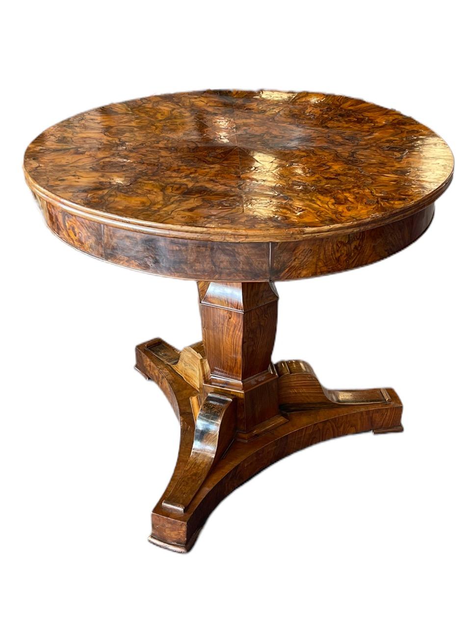 table ronde italienne du XVIe siècle en ronce de noyer. Une colonne et trois pieds faits du même type de bois soutiennent le sommet, qui est découpé en forme de tarte.
 