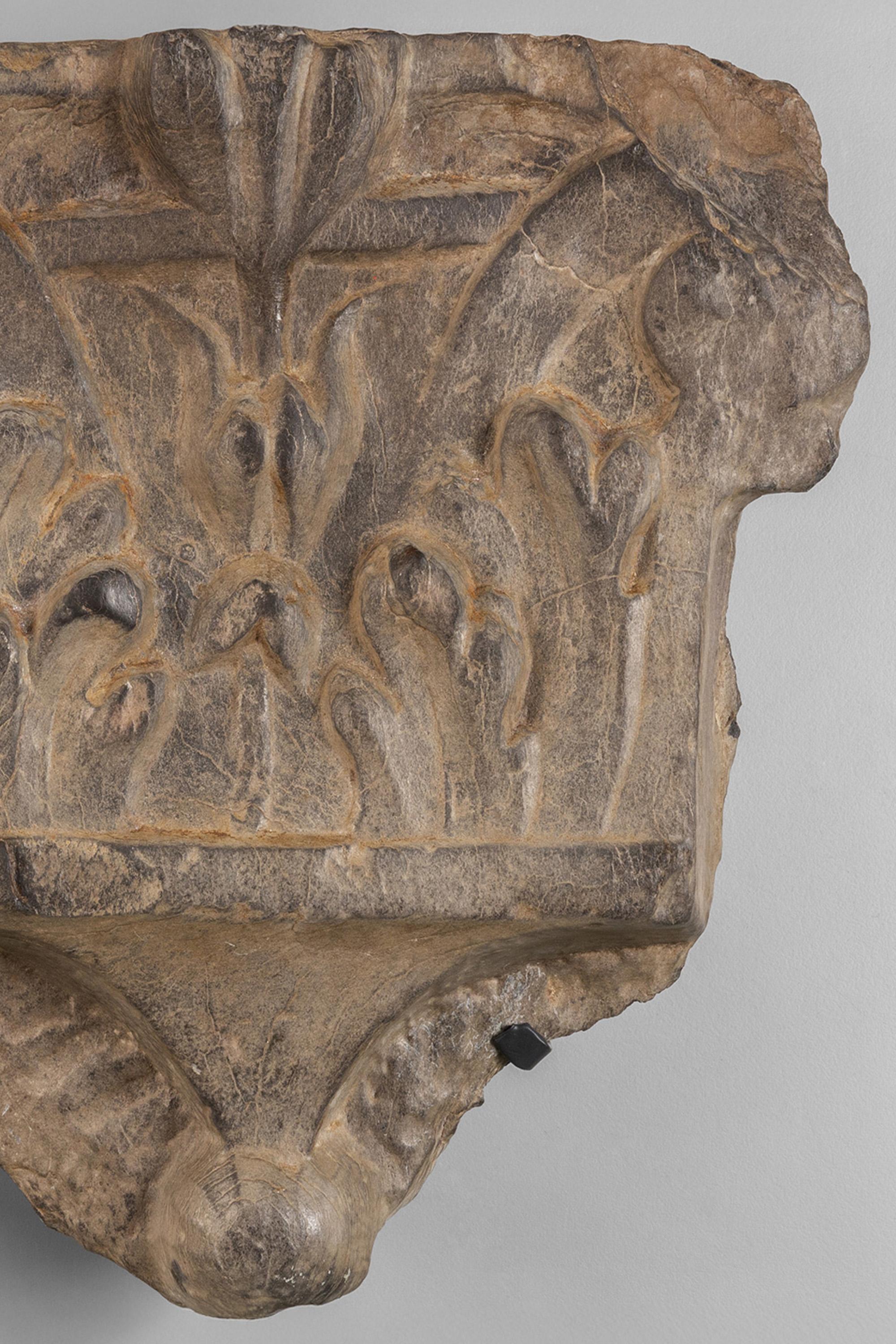 A rare 16th Century Italian stone Corinthian half-capital, carved in Ligurian slate, mounted on a simple wrought iron bracket for wall hanging.

