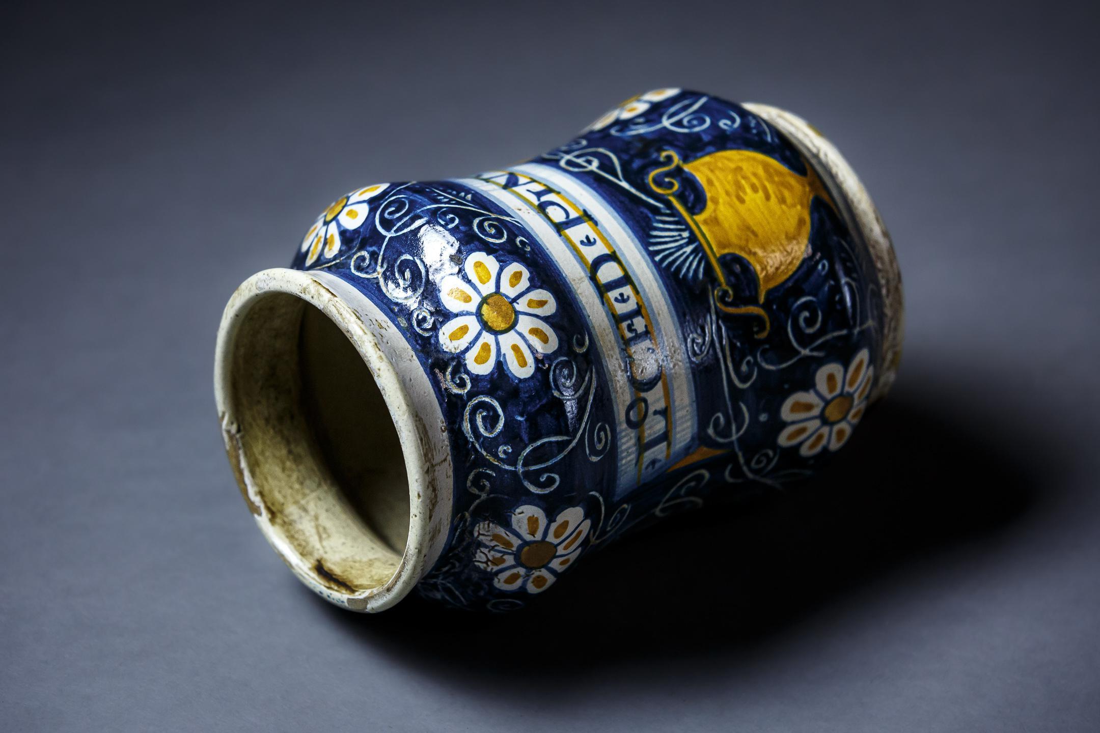 Early Maiolica tin glazed earthernware albarello or pharmacy jar. Painted in blue and yellow, apart from bands around the mouth and base the entire is decorated on blue ground with formal daisy like flowers on stems with tendrils springing from an