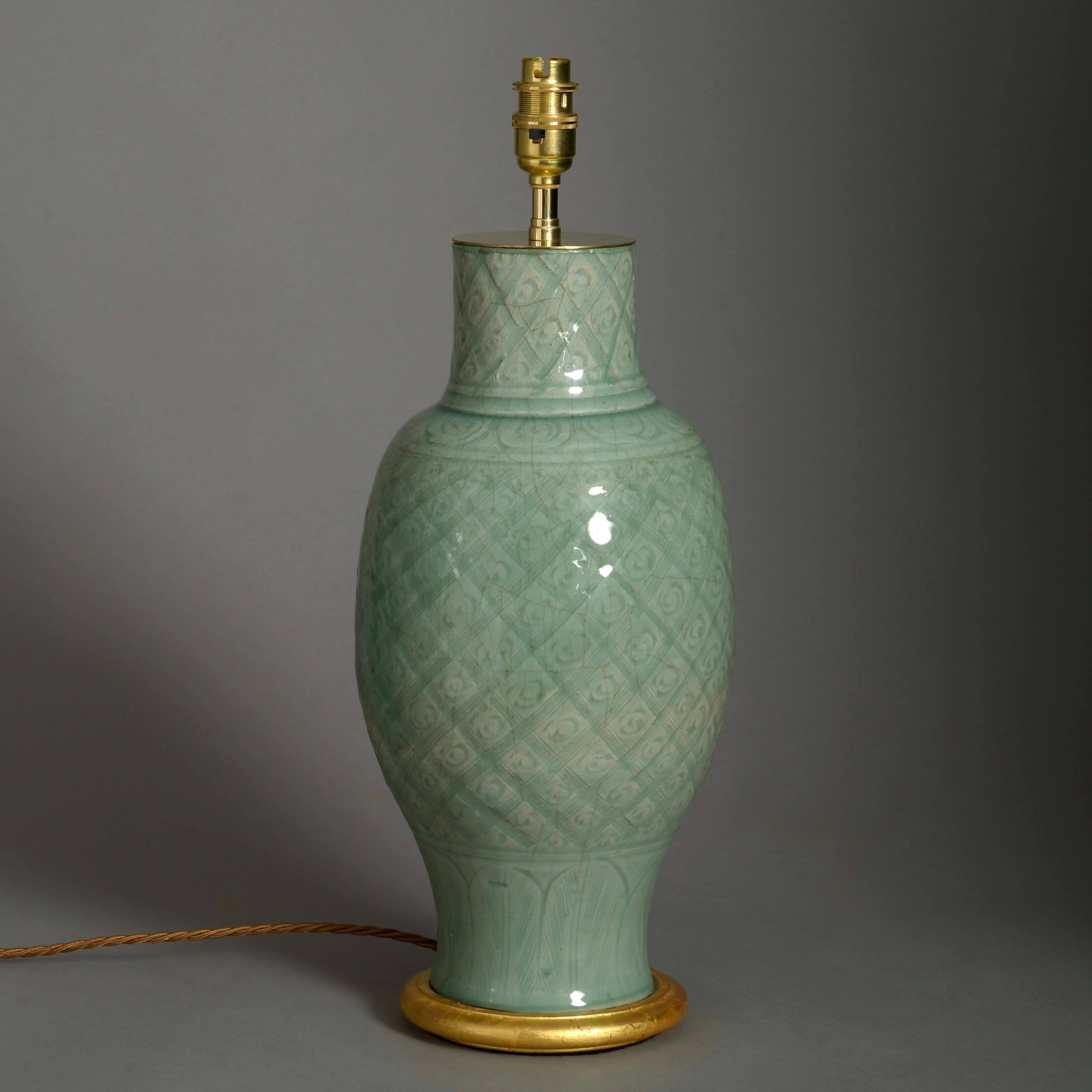 A mid-16th century celadon porcelain vase, the body with inscribed crosshatching and foliate decoration. Now mounted on a turned giltwood base and wired as a lamp. Neck slightly reduced.

Ming Period, circa 1550

Height dimensions refer to vase
