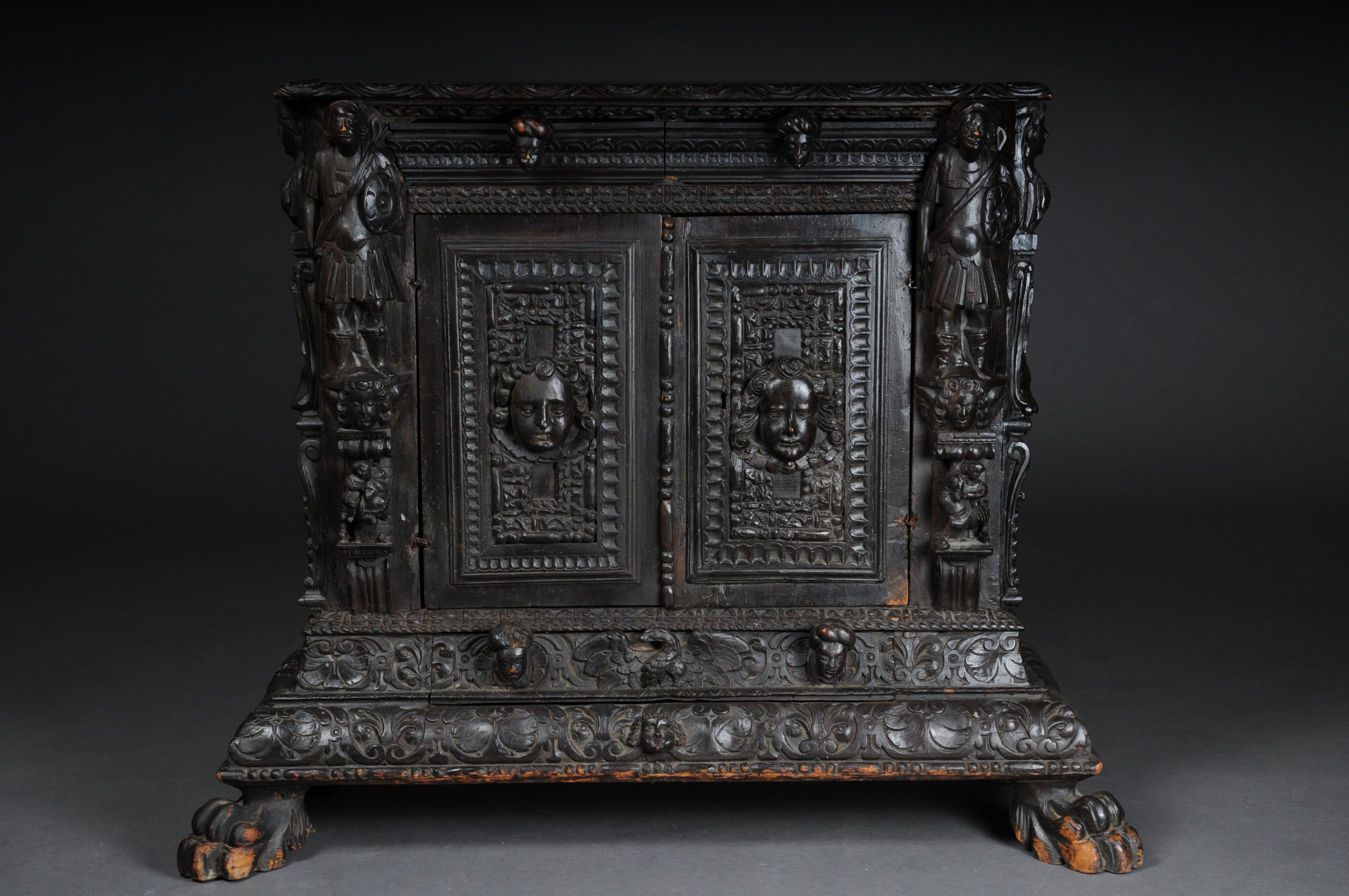 Museum chest of drawers Renaissance probably 16th century

Solid wood blackened two-door body flanked by fully plastic figure elements.
Richly carved carving in the form of grotesque figures / mascarons.
Above the doors there are 2 drawers and a