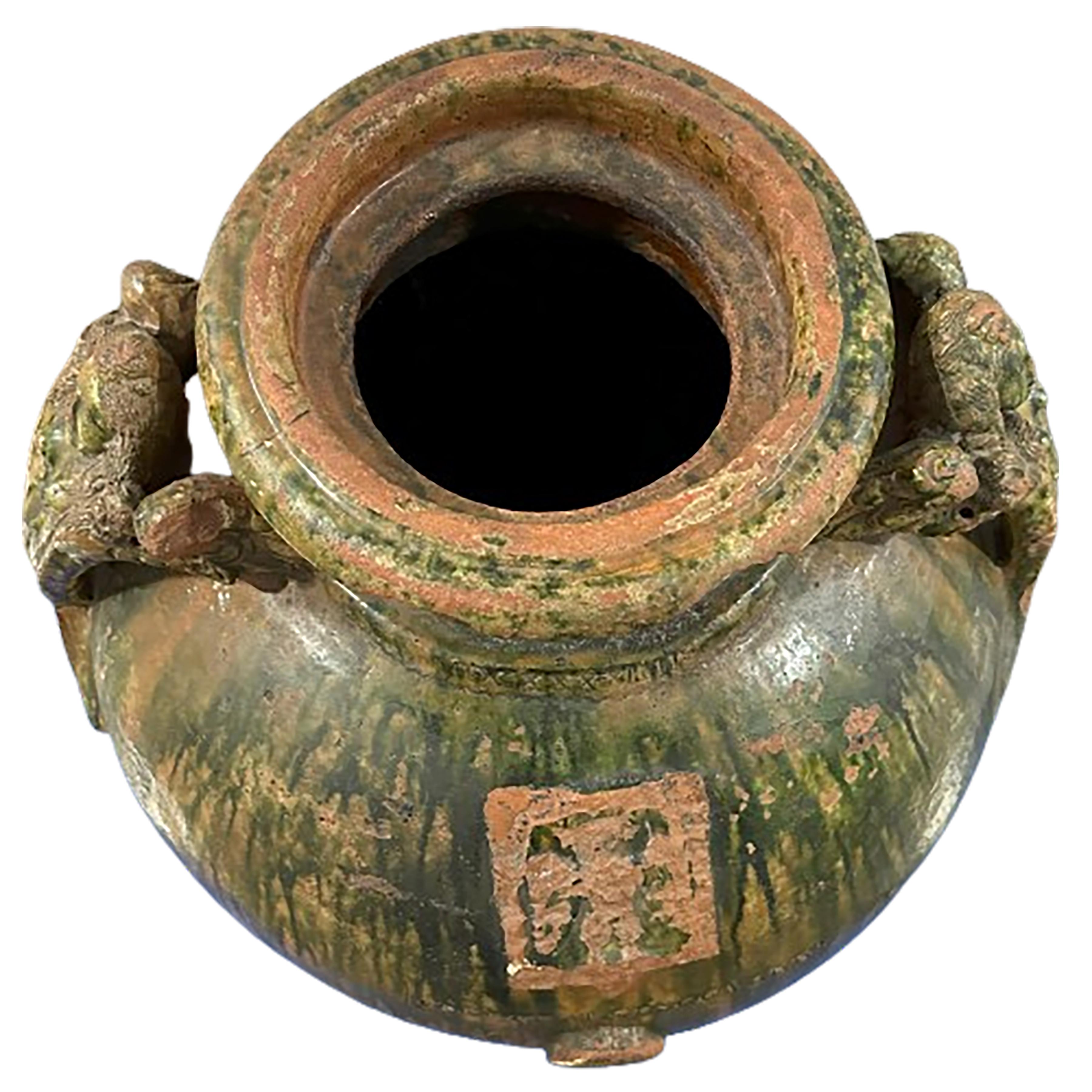 Un affascinante vaso di olive in ceramica italiana con uno smalto verde muschio e giallo ocra bruciato. Sulle maniglie sono scolpiti volti angelici con ali. Feltro sul fondo. Sono inclusi i fori laterali che sarebbero stati utilizzati per versare