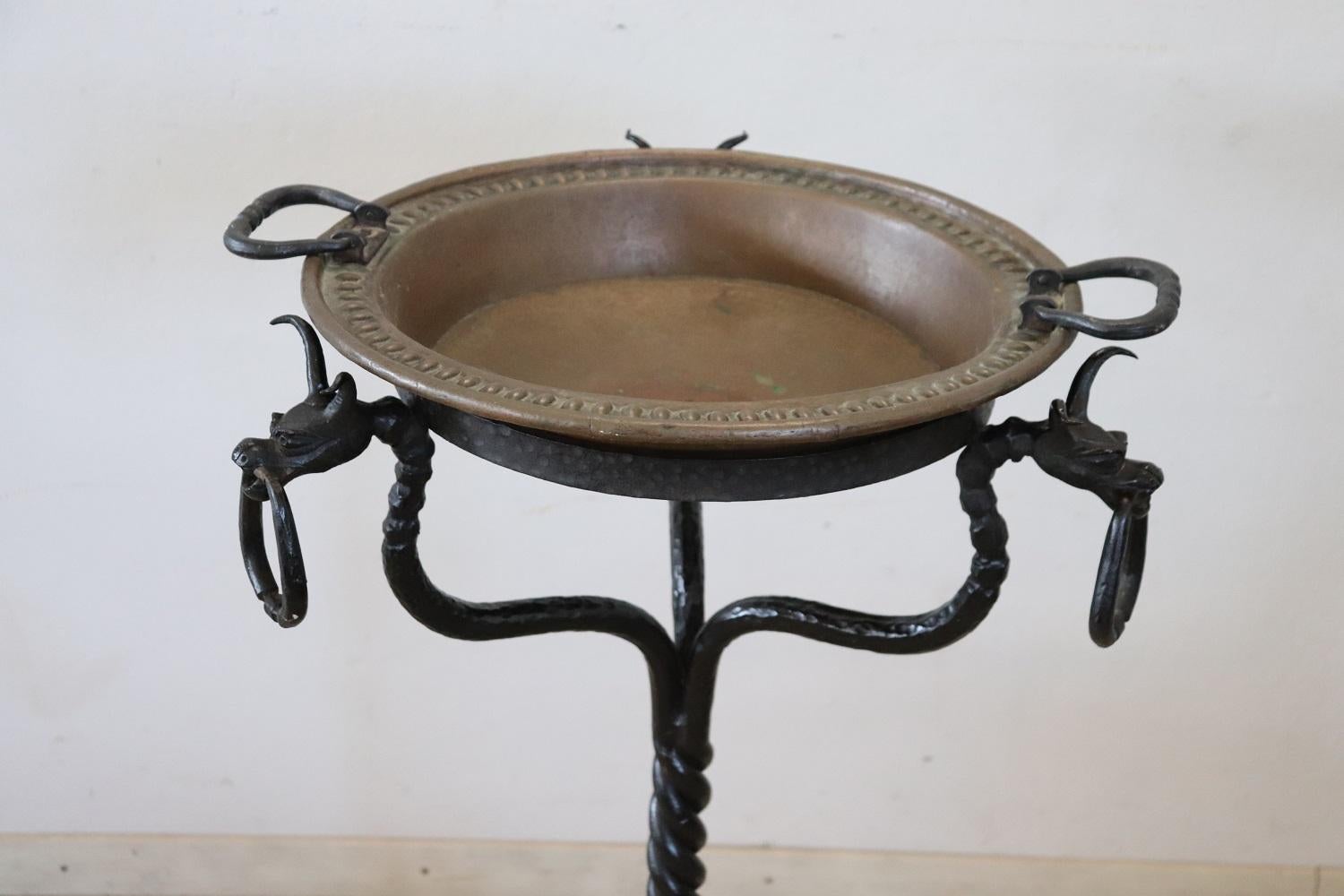 This brazier from the 16th century Renaissance era is truly rare. The fire pit features a copper vessel and a beautifully crafted hand-forged iron pedestal. The pedestal has three feet and a decoration with grotesque figures. The copper vessel is