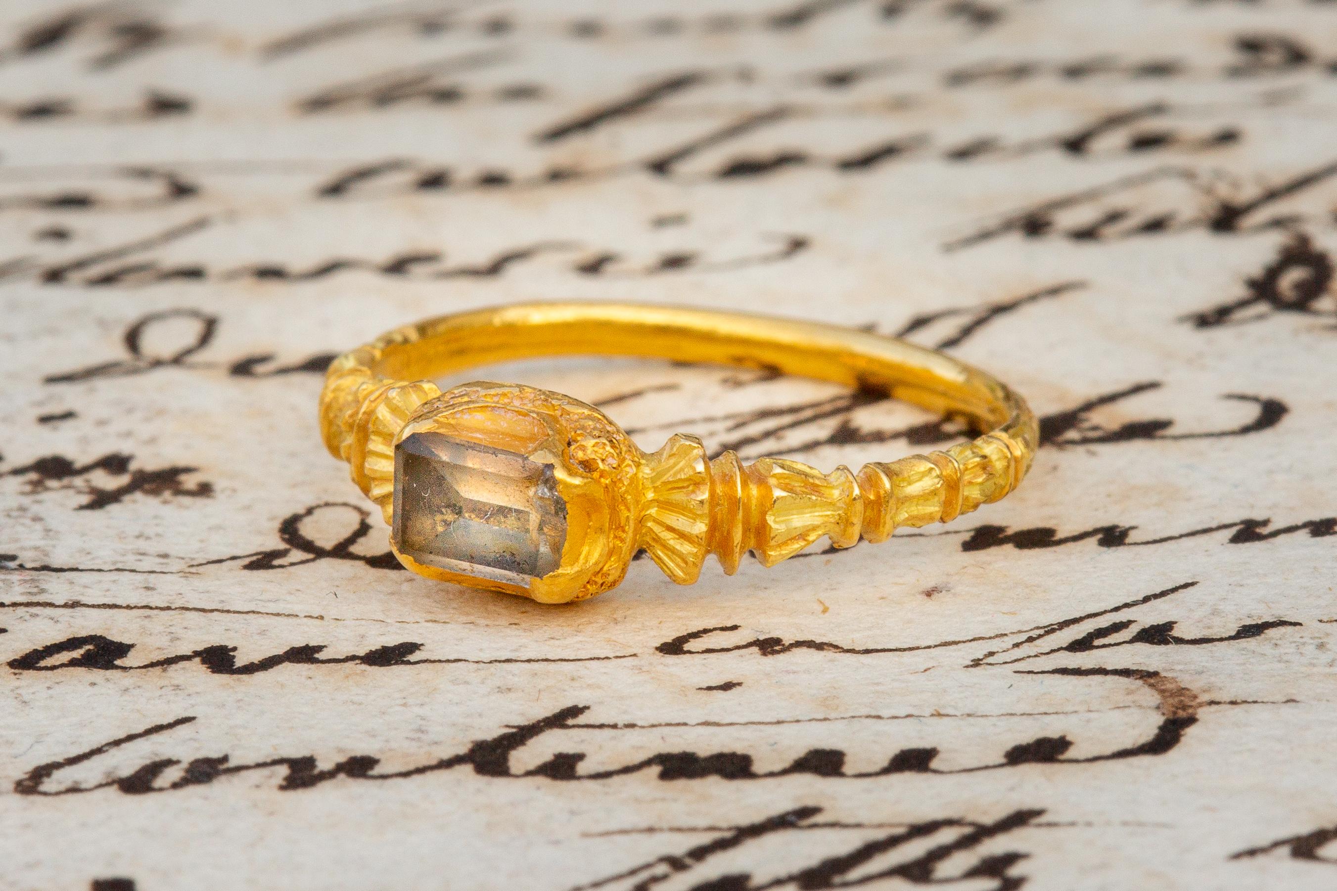 A stunning example of a European renaissance ring dating to 1550-1600! A table-cut rock crystal is mounted in a closed back rub over setting. The quatrefoil bezel is cuffed with a recessed crescent on each side and is flanked by fantastic ornate