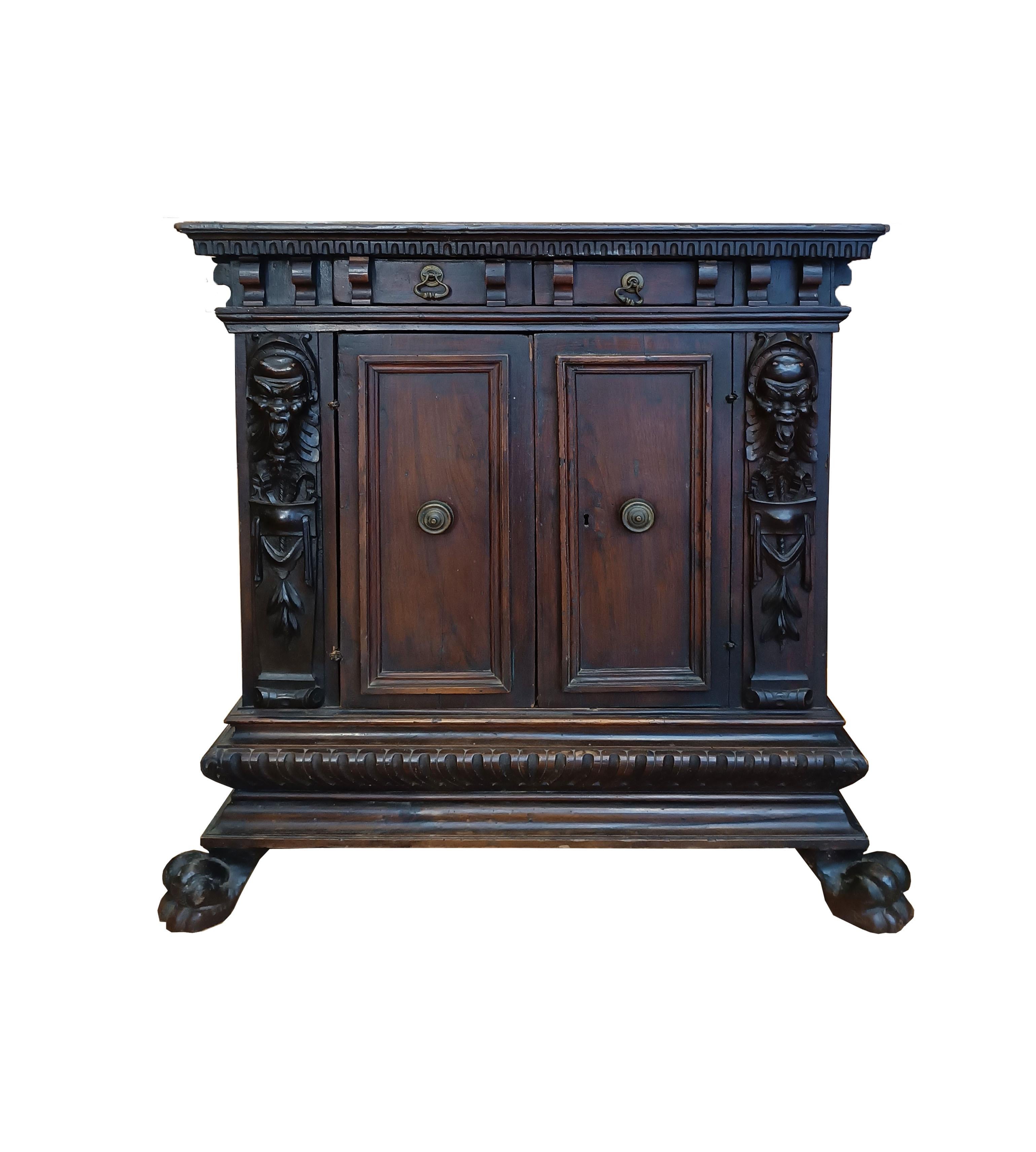 Elegant Renaissance small sideboard, made entirely of solid walnut by Florentine artisans and dating back to the first half of the 16th century. Its structure is composed of two front doors and two drawers, adorned with elegant knob and bell