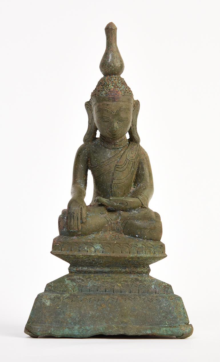 Antique Burmese bronze Buddha sitting in Mara Vijaya (calling the earth to witness) posture on a base.

Age: Burma, Shan Period, 16th Century
Size: Height 16.3 C.M. / Width 8.6 C.M.
Condition: Nice condition overall (some expected degradation due to
