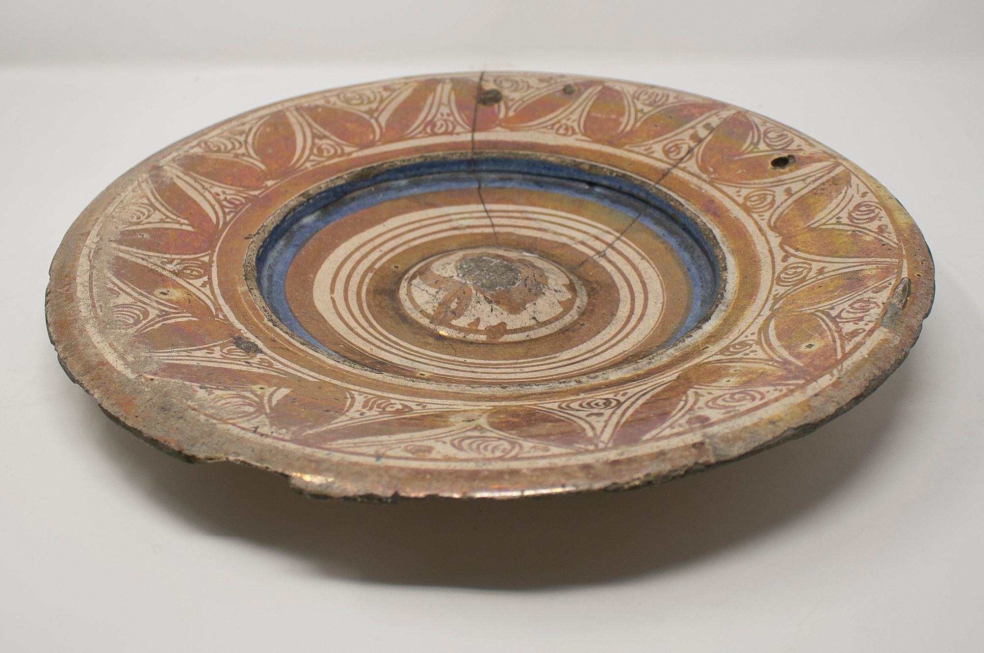 Piatto in lustro spagnolo di Manises del XVI secolo che combina la ceramica con lo smalto metallico.

È stato riparato con grappe di ferro.