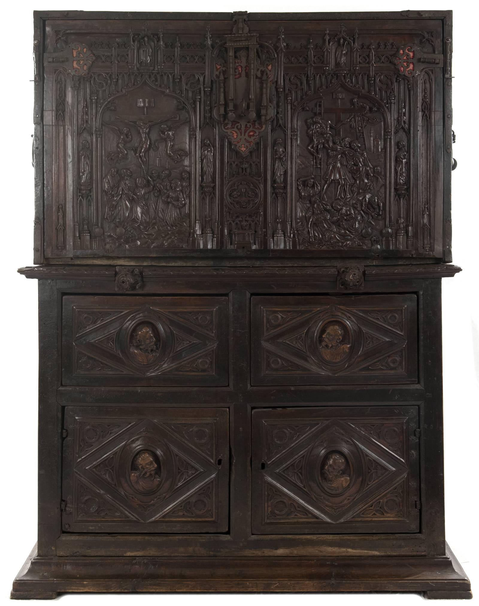 A museum-quality Spanish vargueño or cabinet on stand. When closed the upper portion features a detailed high-relief, multi-figural depiction of the Crucifixion and Lamentation of Jesus Christ. The lower portion has four large panels, each carved