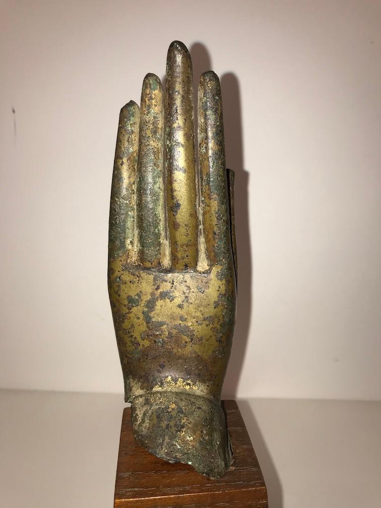 A gilt bronze Buddha hand from Thailand dating to the 16th century. This Fine cast with elegant fingers is mounted on a walnut base. It shows one of the Buddha's ritual gestures, the Abhaya mudra, which represents protection, peace, benevolence, and