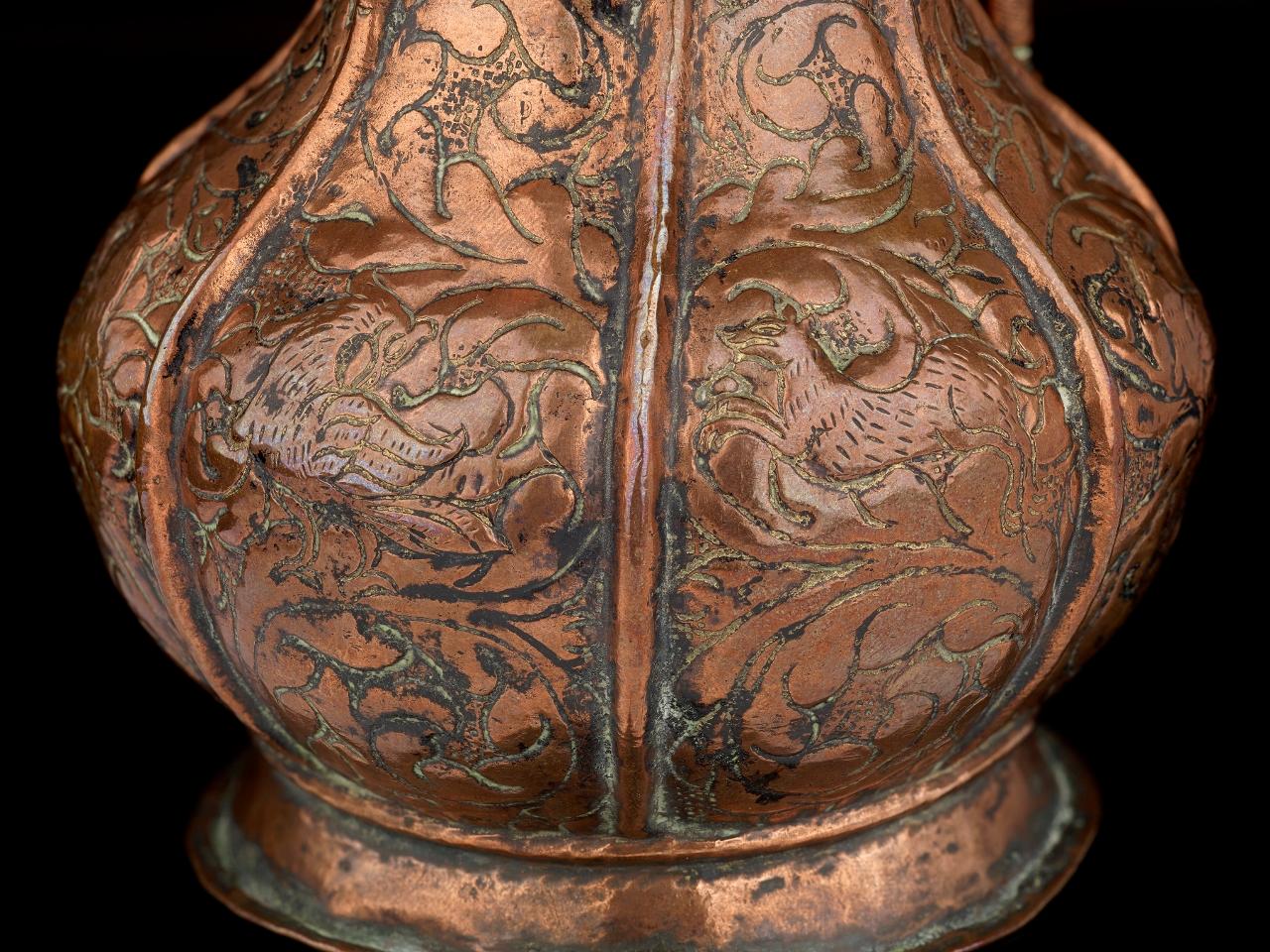 A rare antique 16th century Venetian copper ewer; approximate 8 inches tall; the vertical side panels are intricately chased with birds and hunting dogs surrounded by foliate decoration; the style of the piece is clear evidence of the close links