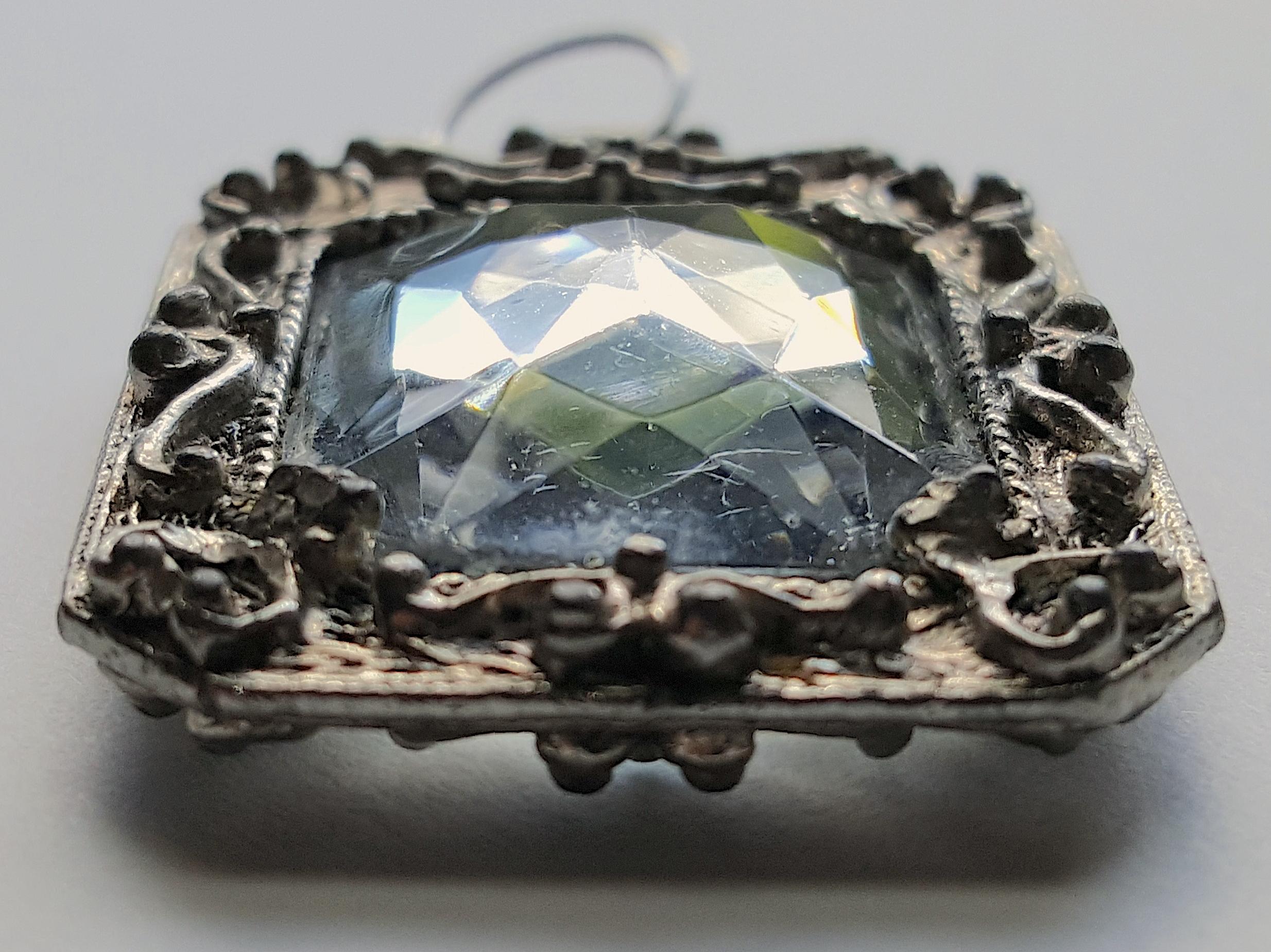 In a rare scissor cut dating to the 1500s, this centuries-old prong-set hogback rock-crystal pendant produces a fascinating play of refractions in low light. With its rectangular narrow-edge silver frame decorated with high-relief curvy scrollwork