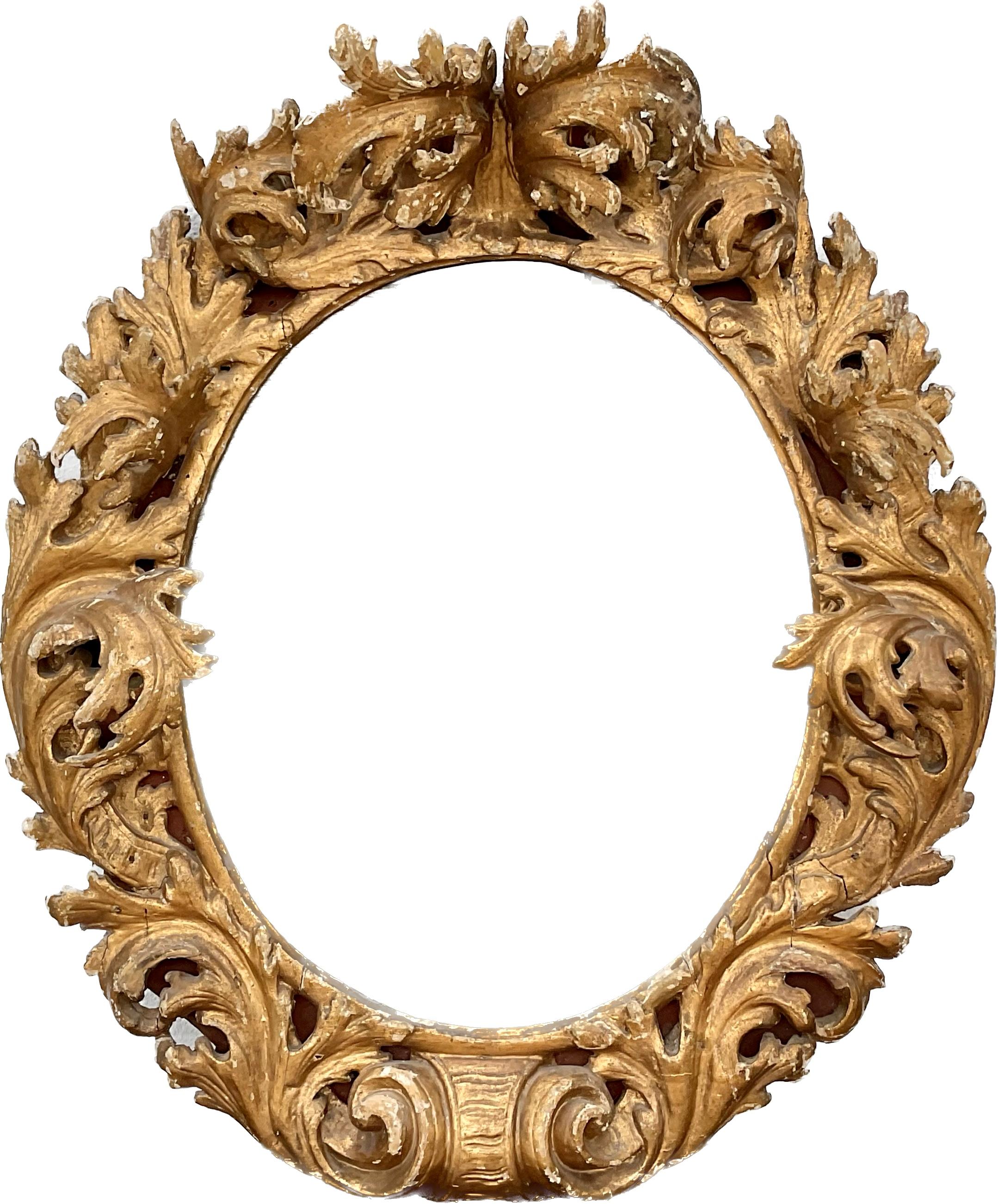 17/18th century heavily hand carved Italian or Spanish Rococo giltwood wall mirror. Mirror is on an oval plate surrounded by carved scrolling acanthus leaves protruding 10 inches or more from the frame. Very nice patina of the gilding. A truly