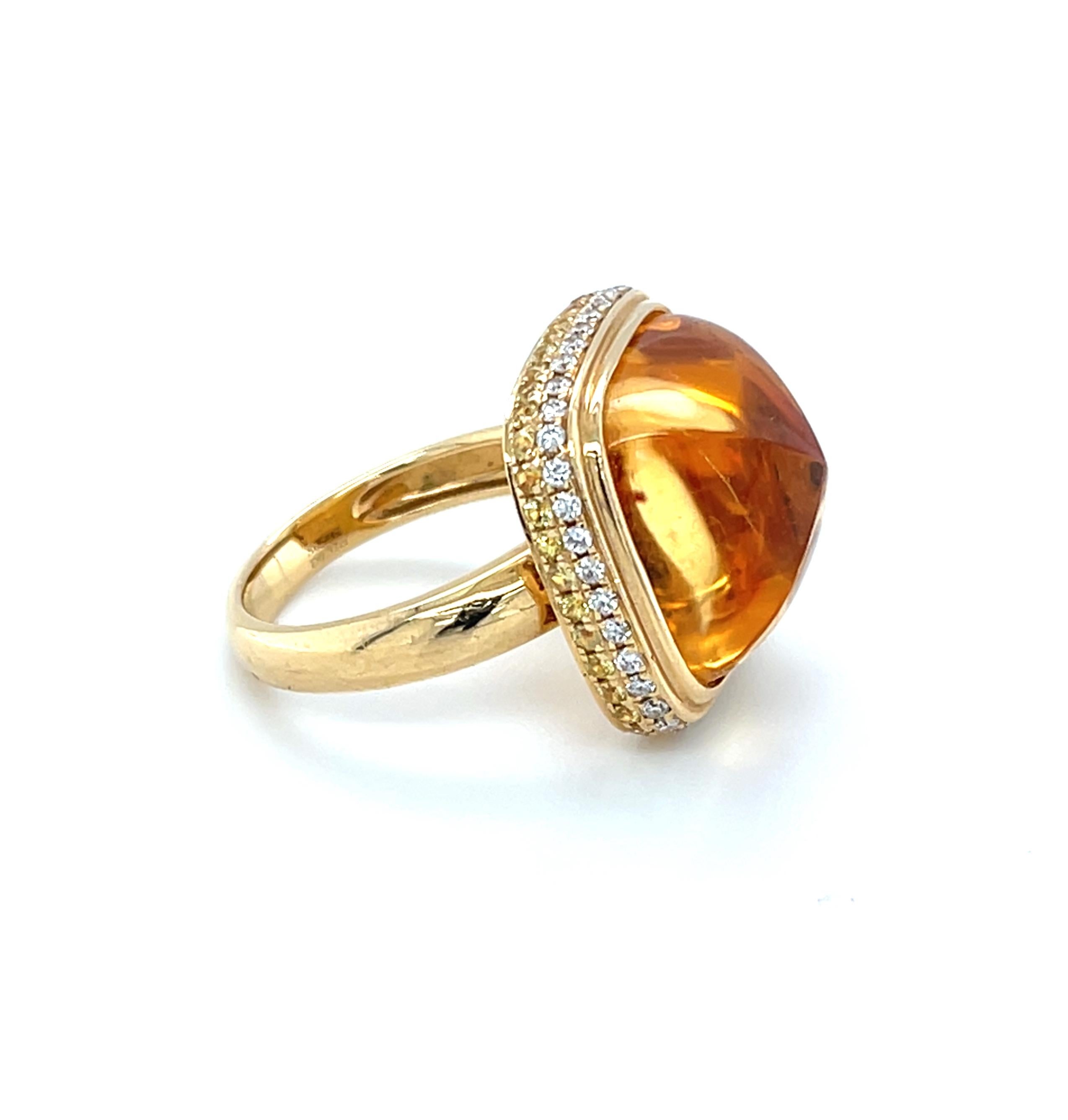 Cette superbe bague présente un magnifique cabochon de citrine en pain de sucre de 17,02 carats serti de diamants blancs naturels brillants et de saphirs jaunes fantaisie dans une bague en or jaune 18 carats fabriquée à la main. La citrine est un 