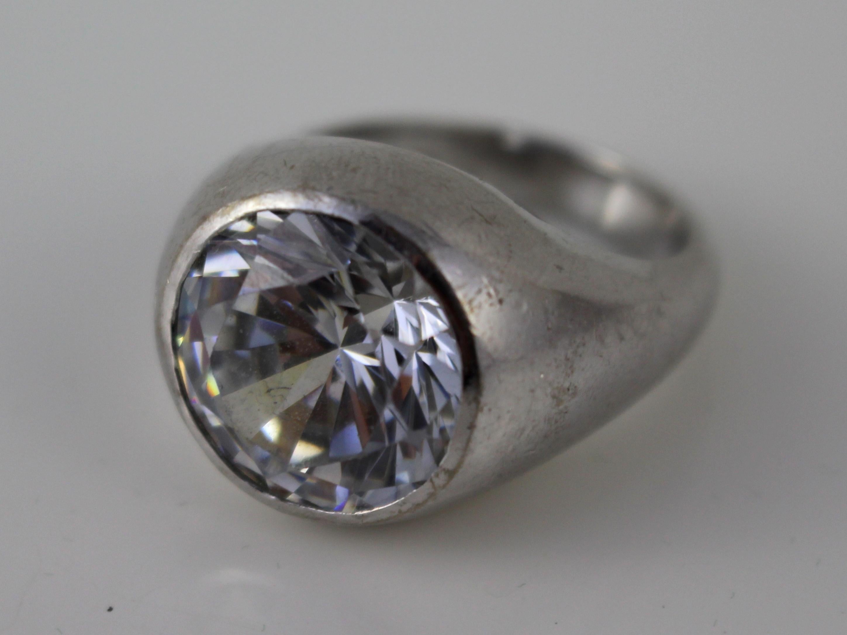 Stone round mixed cut colourless cubic zirconia, measuring approximate 15.3 mm diameter, depth 9.44 mm. Estimated carat weight 17.00 carat, light surface wear
Setting Rub over setting into tapering white mount measuring approximate 17.6 mm at