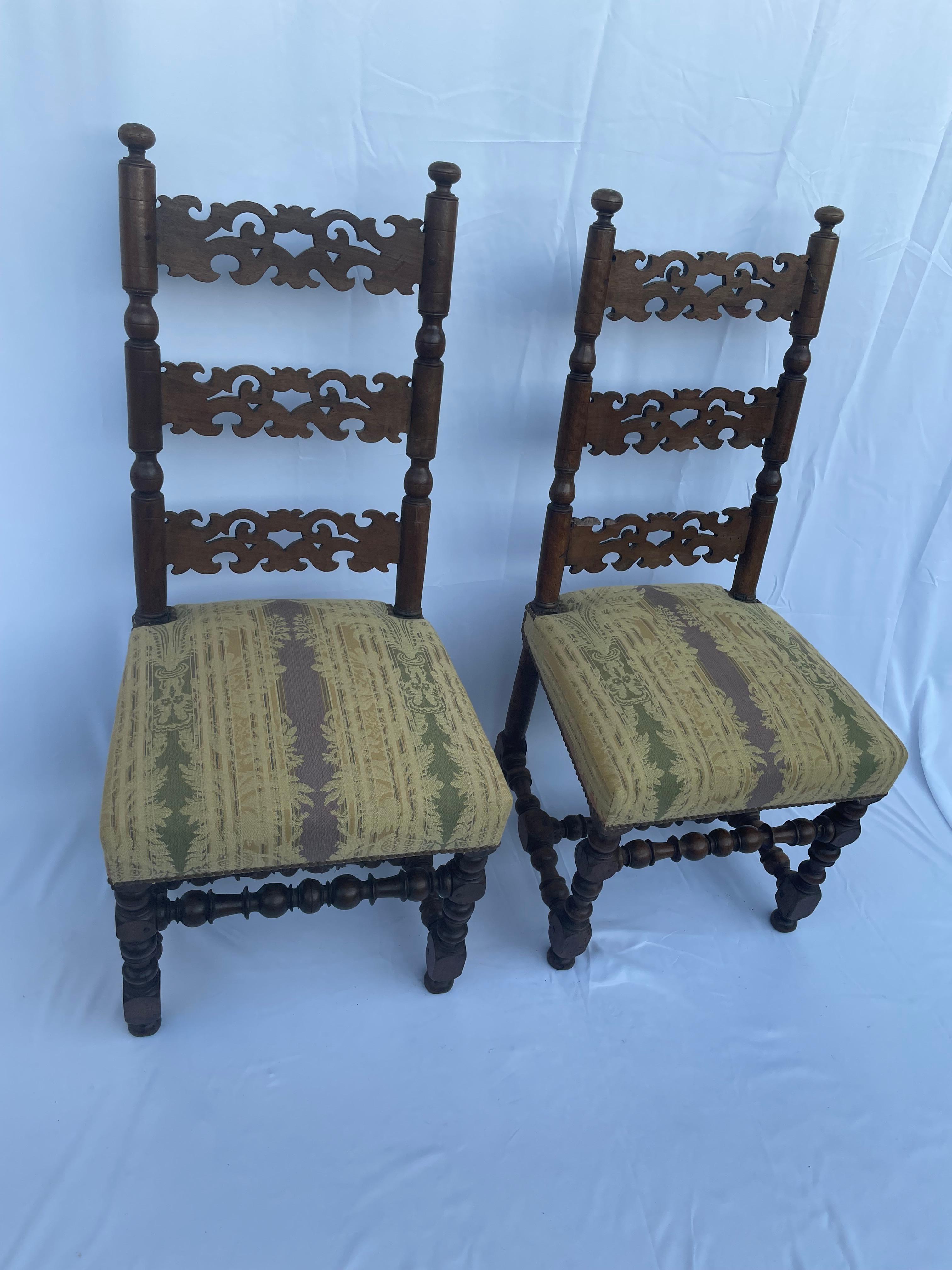 Beautiful pair of French walnut chairs from the 17th century, with twisted legs and cushioned seats. The chairback is nicely done and openly worked in three parts. The cushioned seats are in mustard tones and rich in details, the pattern represents