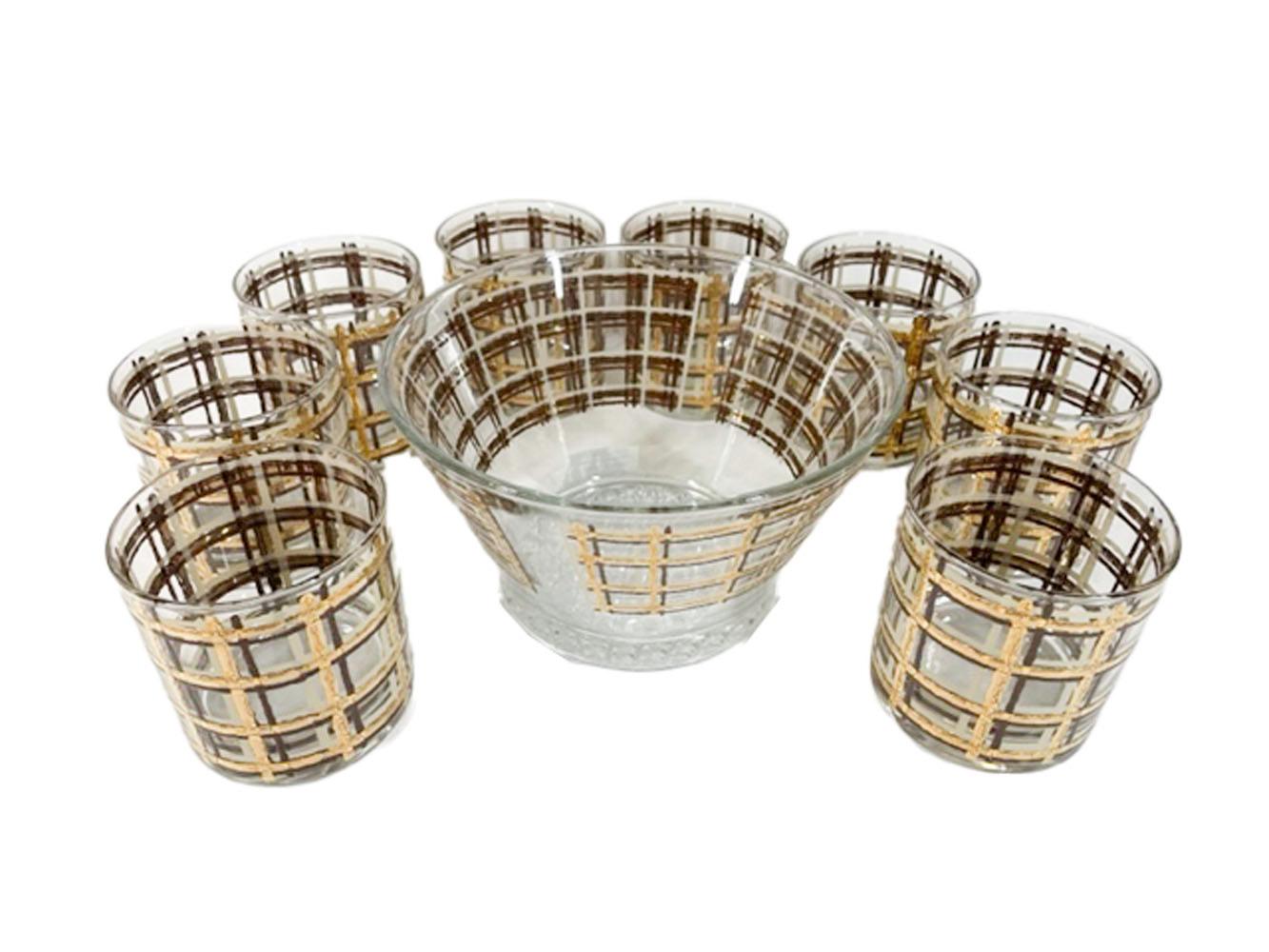 17 Piece Mid-Century Modern barware set consisting of an ice bowl with flared sides and lattice molded foot, 8 highball glasses and 8 rocks glasses. Each piece decorated with loose wavey lines in cream and brown enamel with 22 karat gold in a plaid