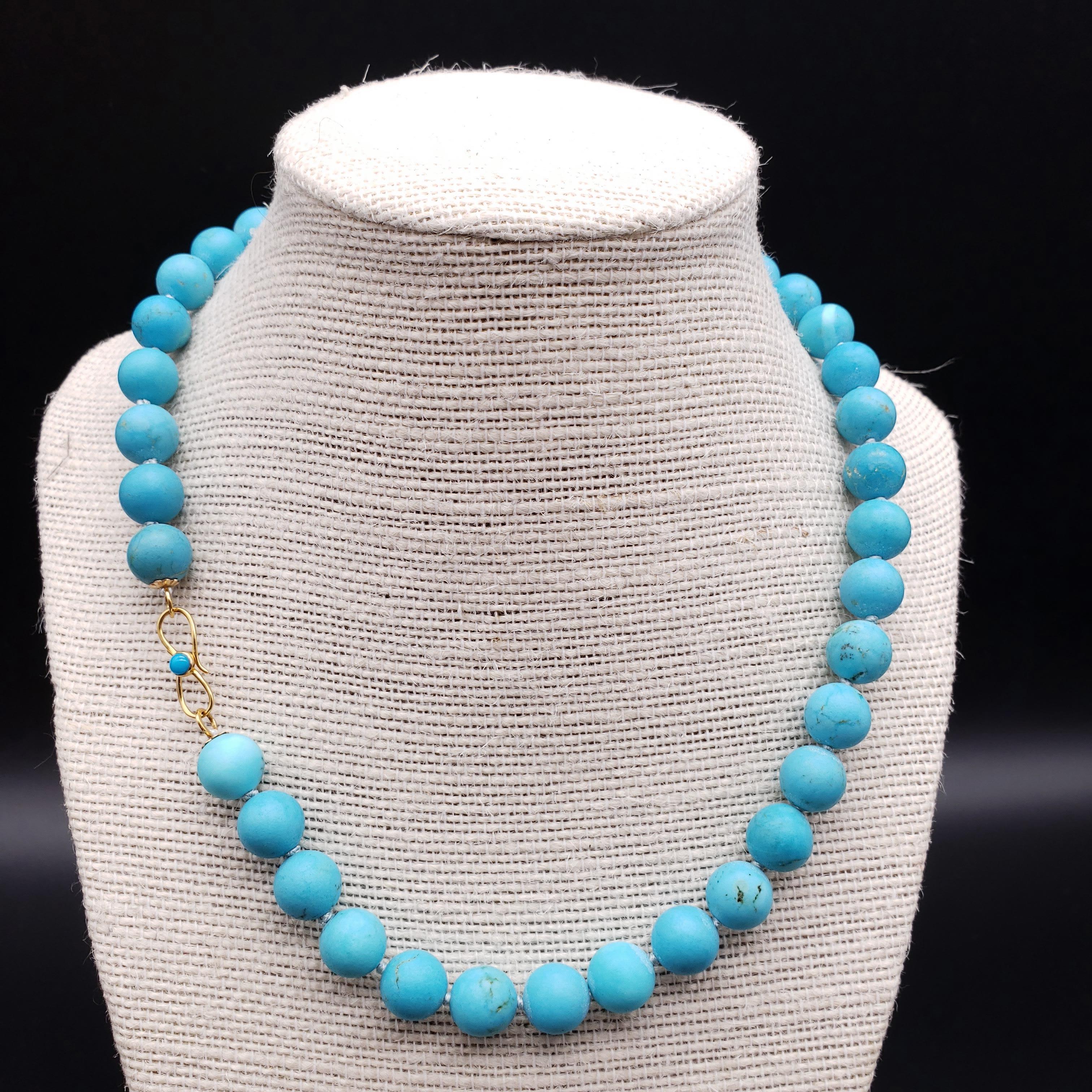 A regal necklace! Genuine sleeping beauty turquoise beads hang on a teal knotted string necklace, accented with a luxurious 18K yellow gold clasp.

Bead diameter approx 10mm
Hallmarks: 18K  