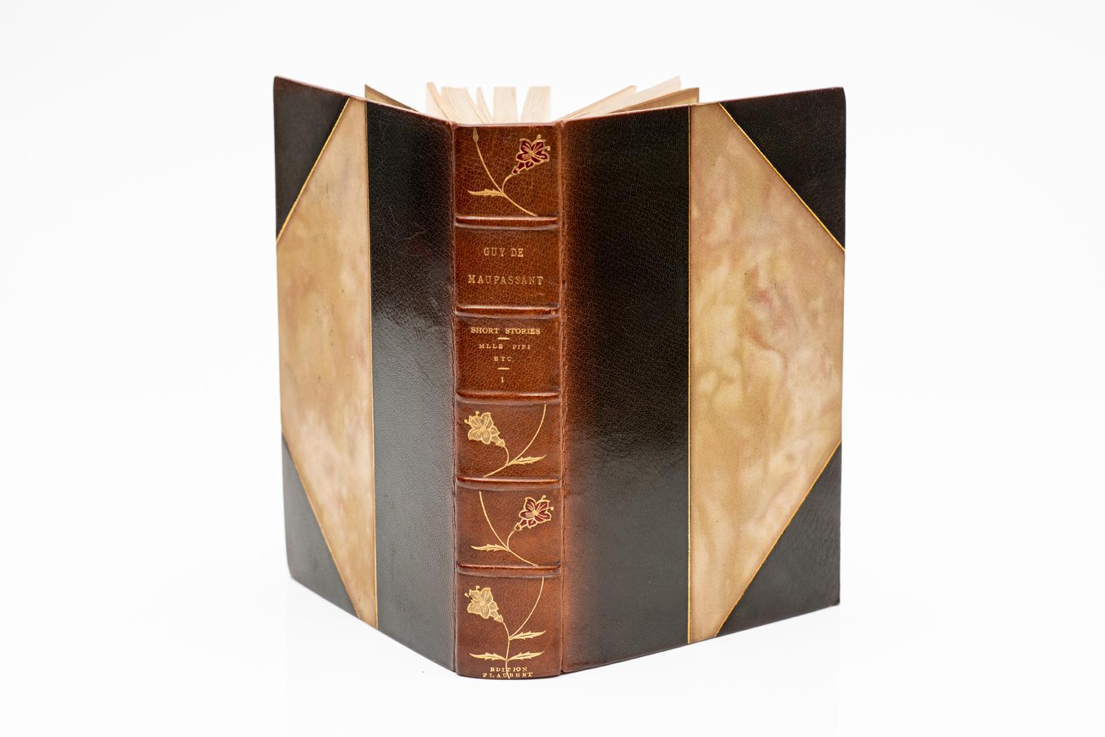 17 Volumes. Guy DeMaupassant. The Life and Works. Bound in 3/4 tan morocco, marbled boards and endpapers, top edges gilt, raised bands, floral gilt inlays on spines, Illustrated from original drawings by Eminent French and American artists, limited