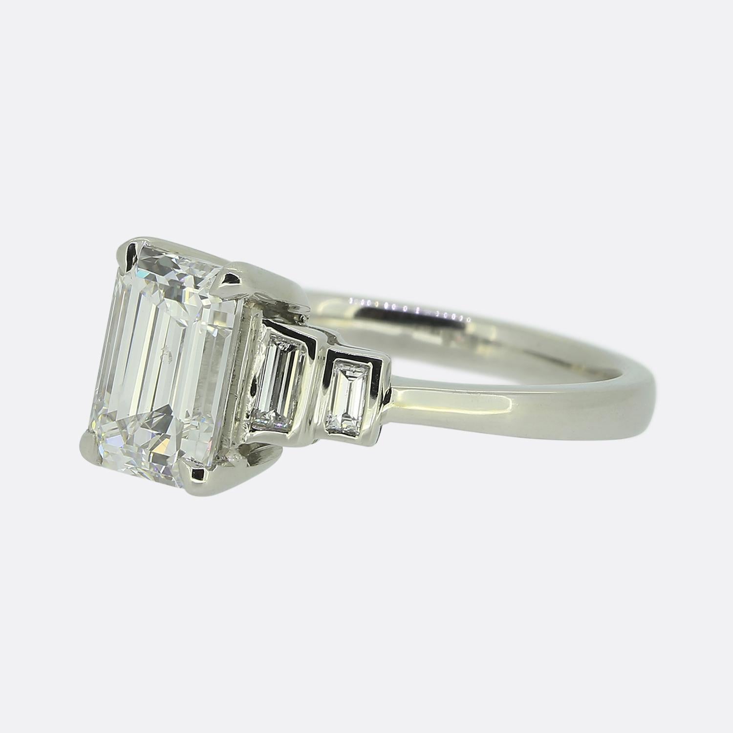 Ecco un anello di fidanzamento con diamante in platino in stile Art Déco. Il punto focale di questo gioiello è un diamante certificato da 1,70 carati con taglio smeraldo che si trova leggermente rialzato in un'incastonatura a quattro griffe al