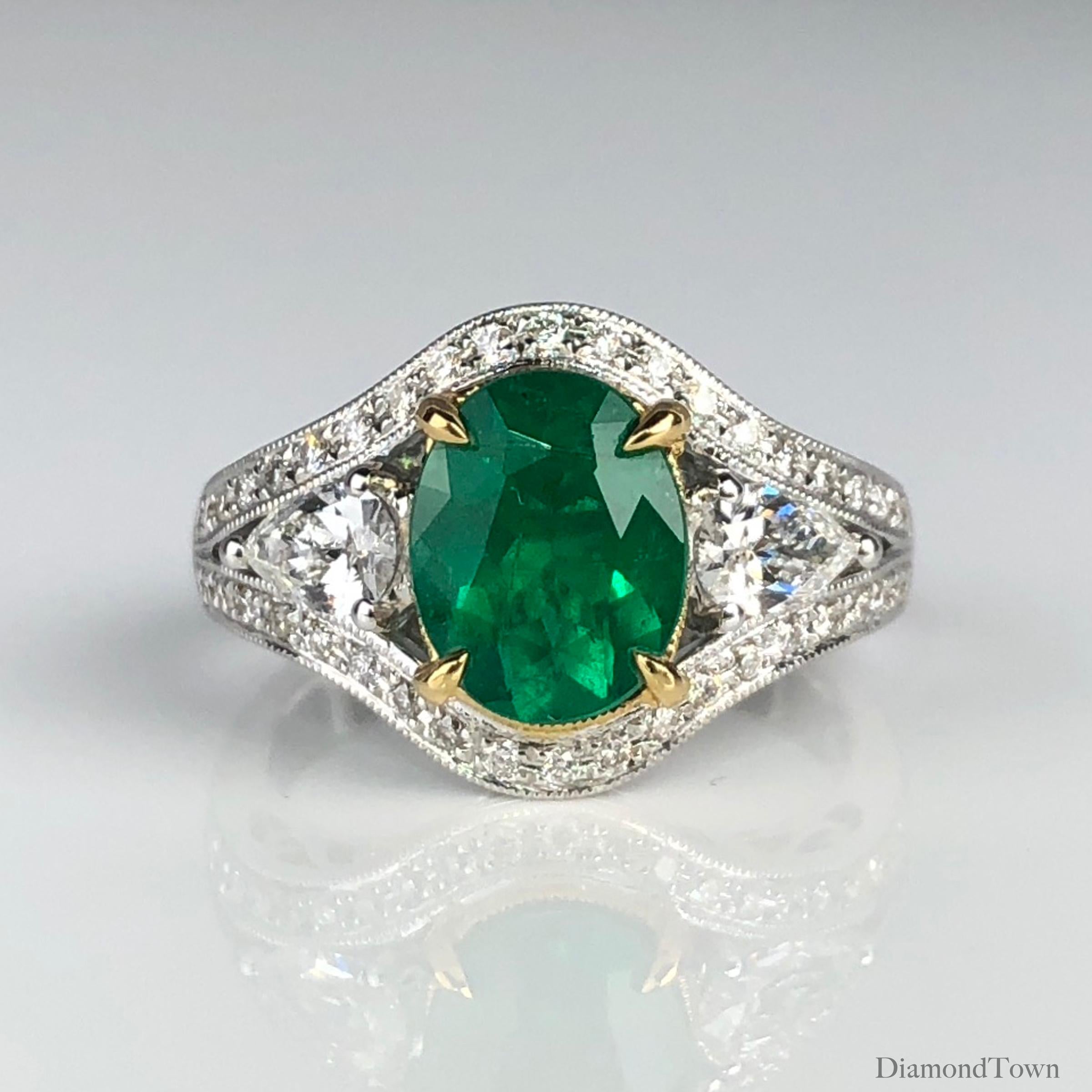 (DiamondTown) This sparkling ring features a 1.70 carat oval cut fine emerald center, flanked by pear shape diamonds and surrounded by a halo of round diamonds extending down a split shank.

The center is set in a yellow gold accent, highlighted