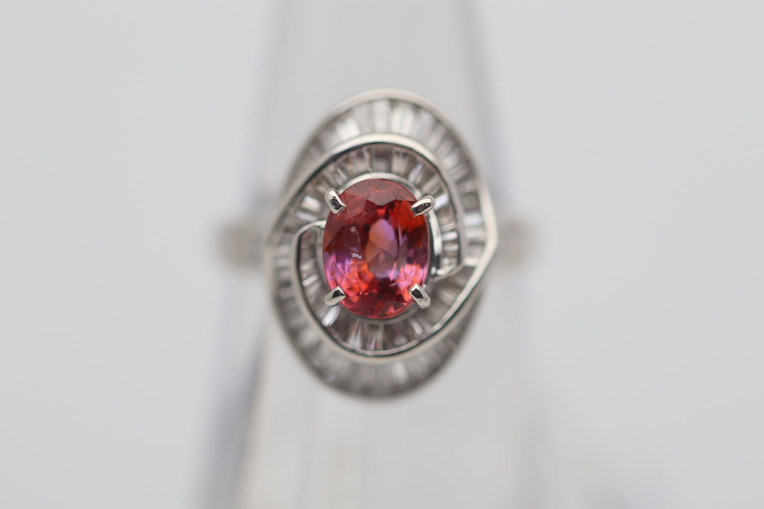 A classic, true gem-quality Ceylon Padparadscha sapphire takes center stage of this platinum made ring. It has the classic pink-orange color which is more intense and vivid then we usually see. The color saturation and brilliance of the stone really