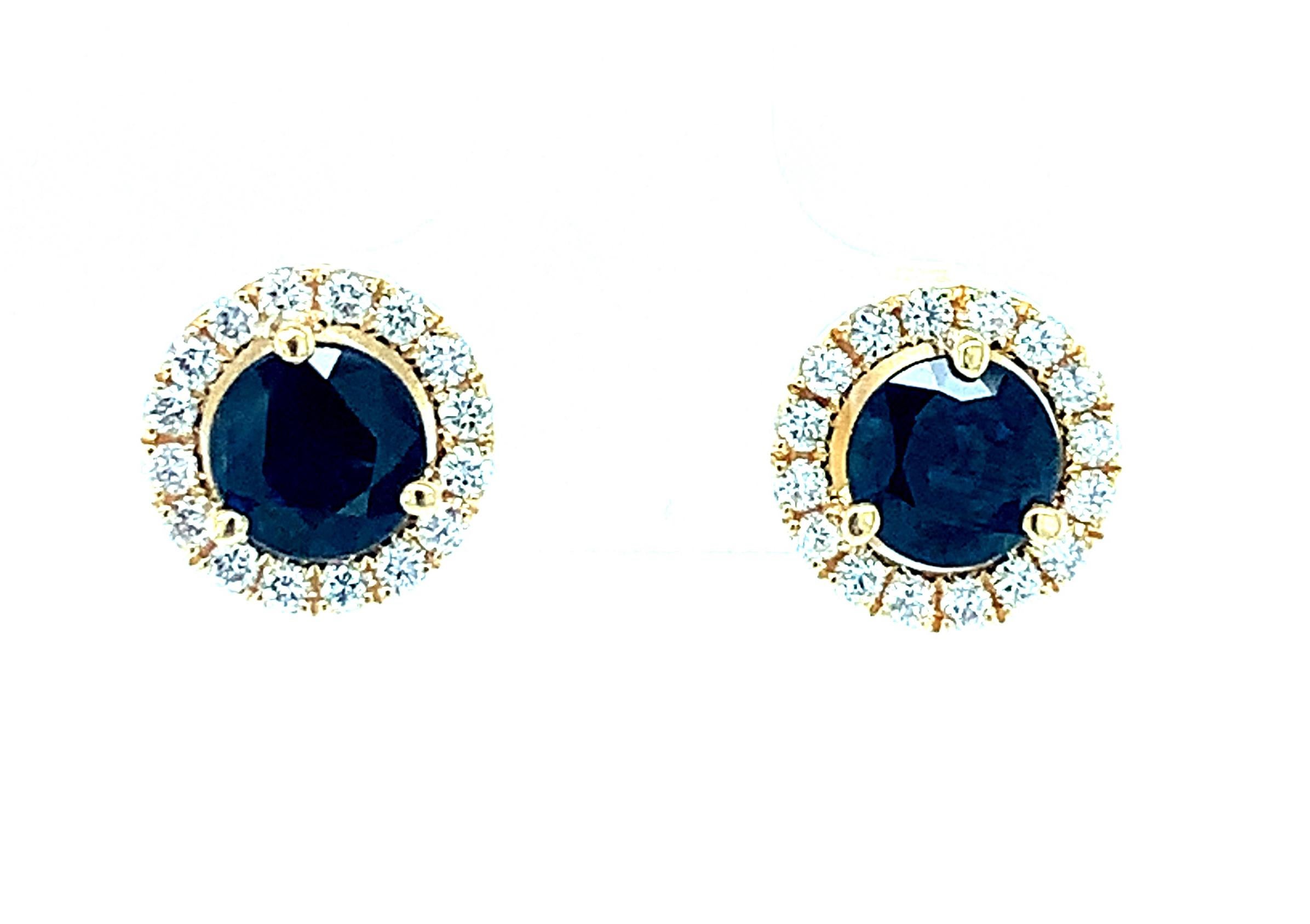 Ces somptueux clous d'oreilles en saphir bleu foncé sont indispensables ! Deux saphirs bleus sont entourés d'un halo de diamants ronds de taille brillant étincelants. Fabriqué à la main par nos maîtres joailliers à Los Angeles en or jaune 18 carats.