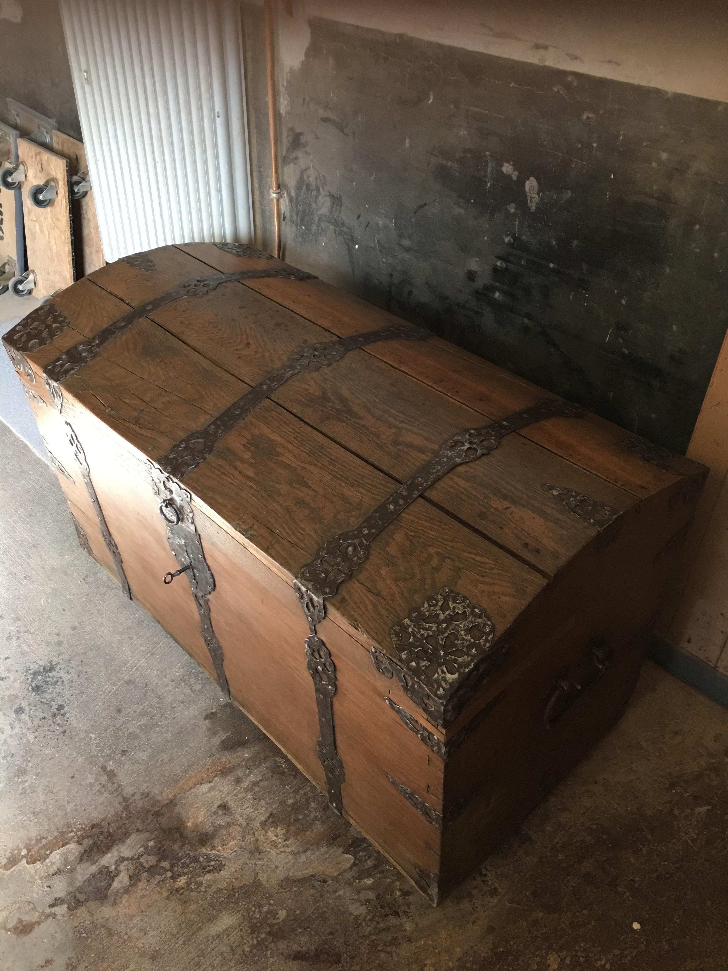 This is an antique Baroque round lid chest with iron ornaments all around. The piece is made of finest oakwood, which has been hand polished with shellac. Forged handles, lid lock in oak and standing on runners feet. The piece shines through the