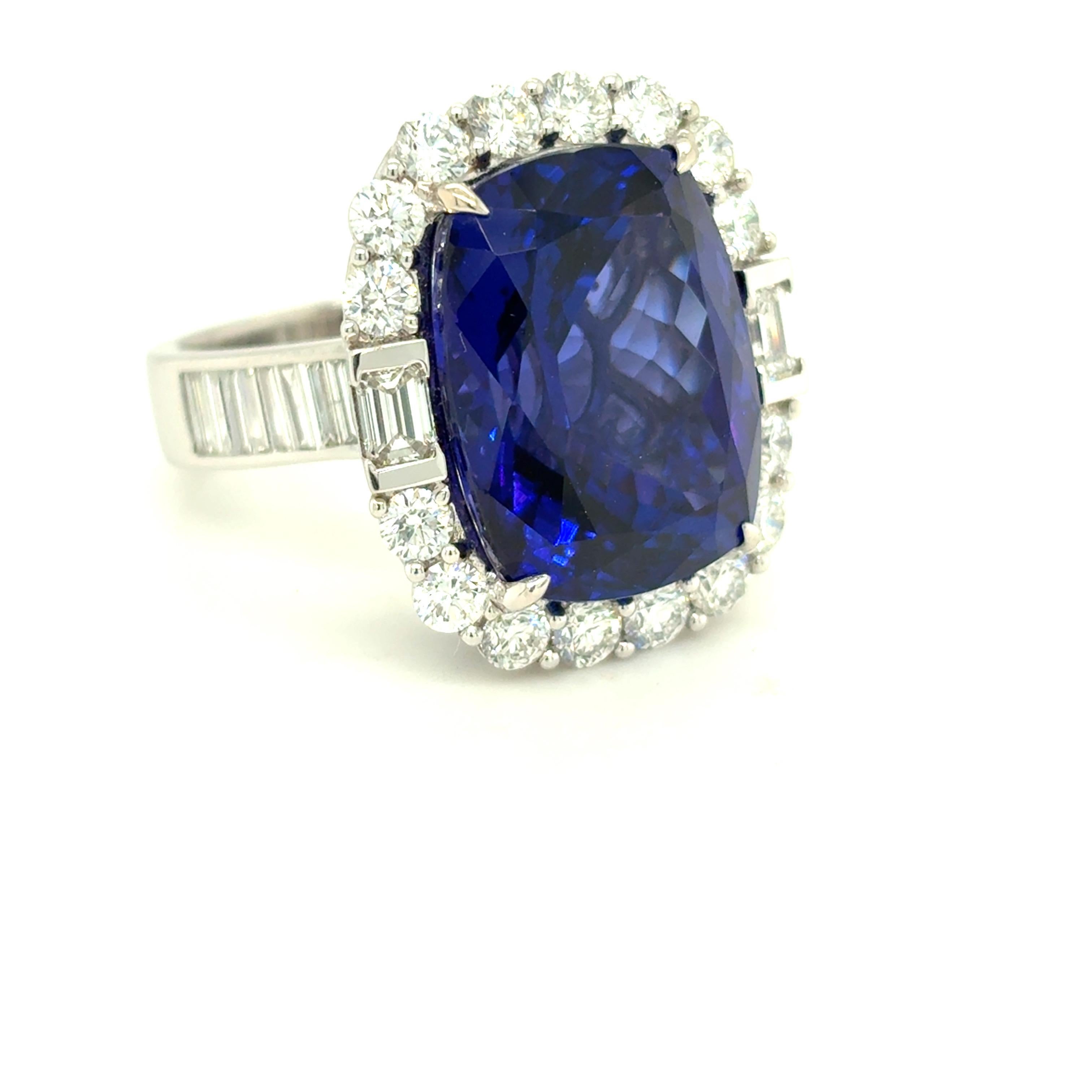 Ein fesselnder Tansanit im Kissenschliff von 17,09 Karat steht im Mittelpunkt dieses eleganten Rings, der von einem Halo aus runden weißen Brillanten eingerahmt wird. Zwei Diamanten im Smaragdschliff akzentuieren die Ost- und Westseite und sorgen