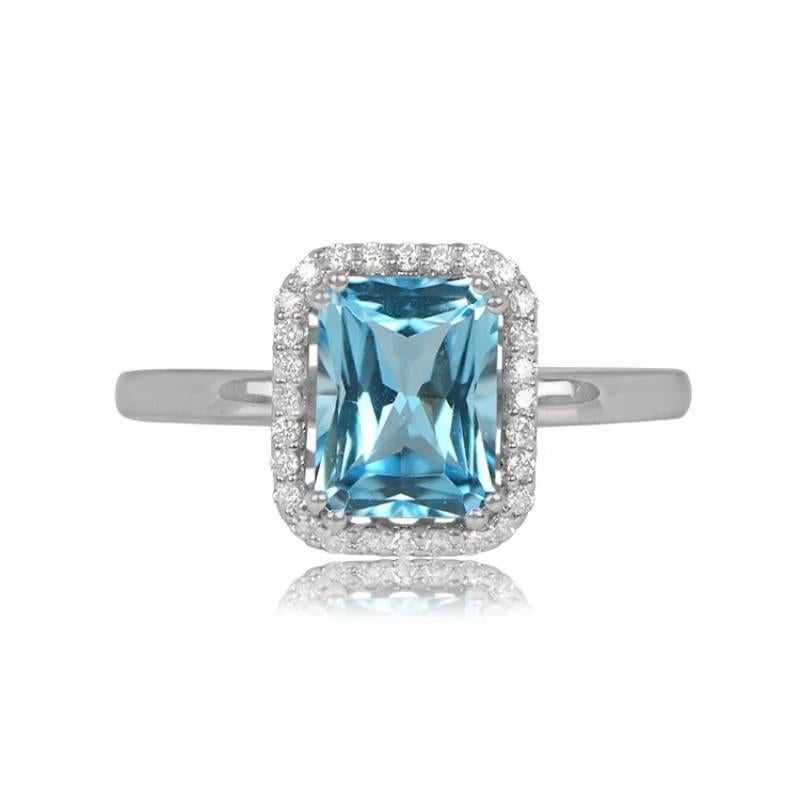 A December birthstone ring showcasing a vibrant 1.70-carat blue topaz with a London blue saturation. The center gemstone is surrounded by a row of white diamonds totaling approximately 0.13 carats. Crafted in 18k white gold, the ring features a