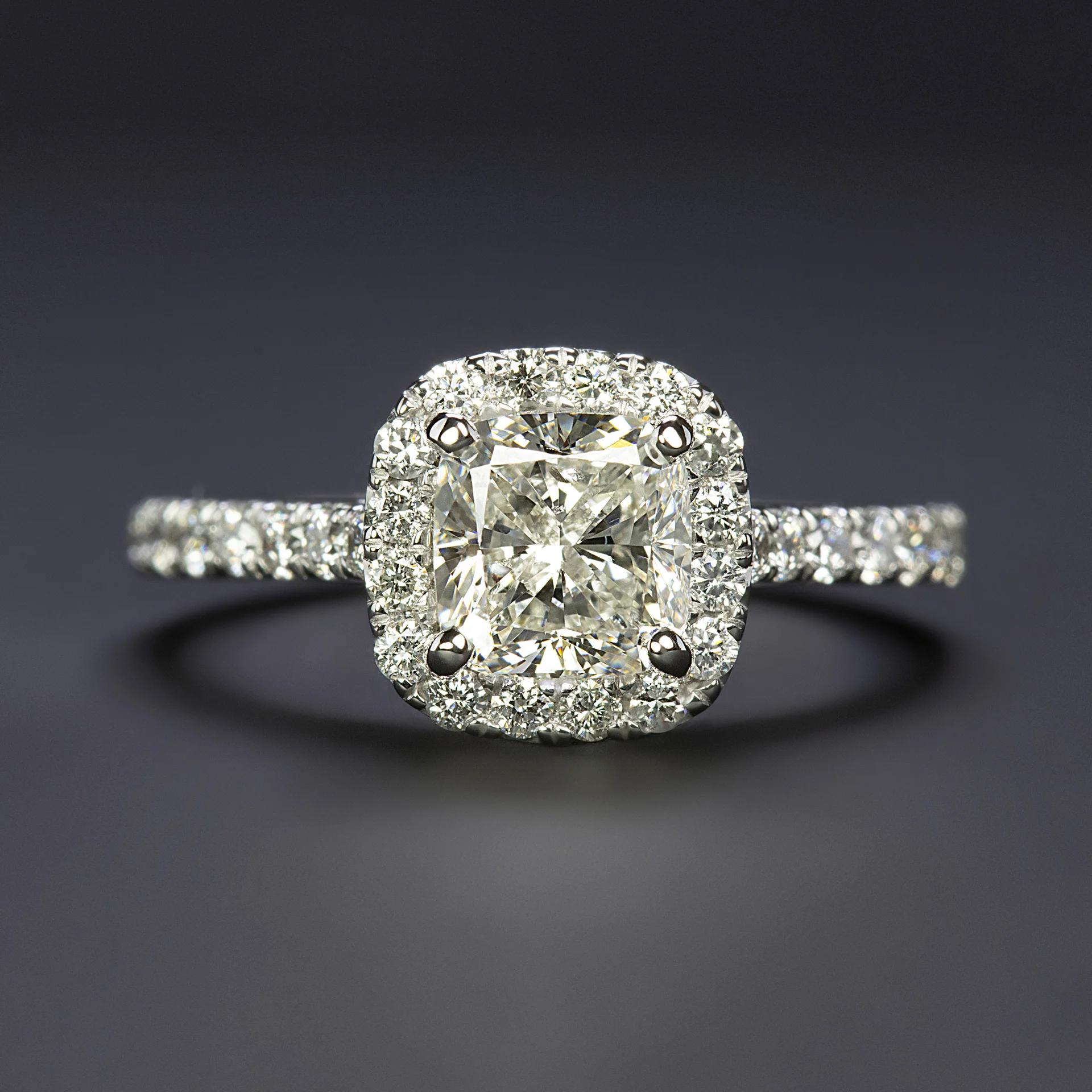 This captivating engagement ring is crafted in high-quality platinum, weighing 4.1 grams, and is designed in a size 5.5 to fit elegantly on the finger. 
At its heart, the ring features a substantial 1.20 ct cushion cut diamond, GIA certified for
