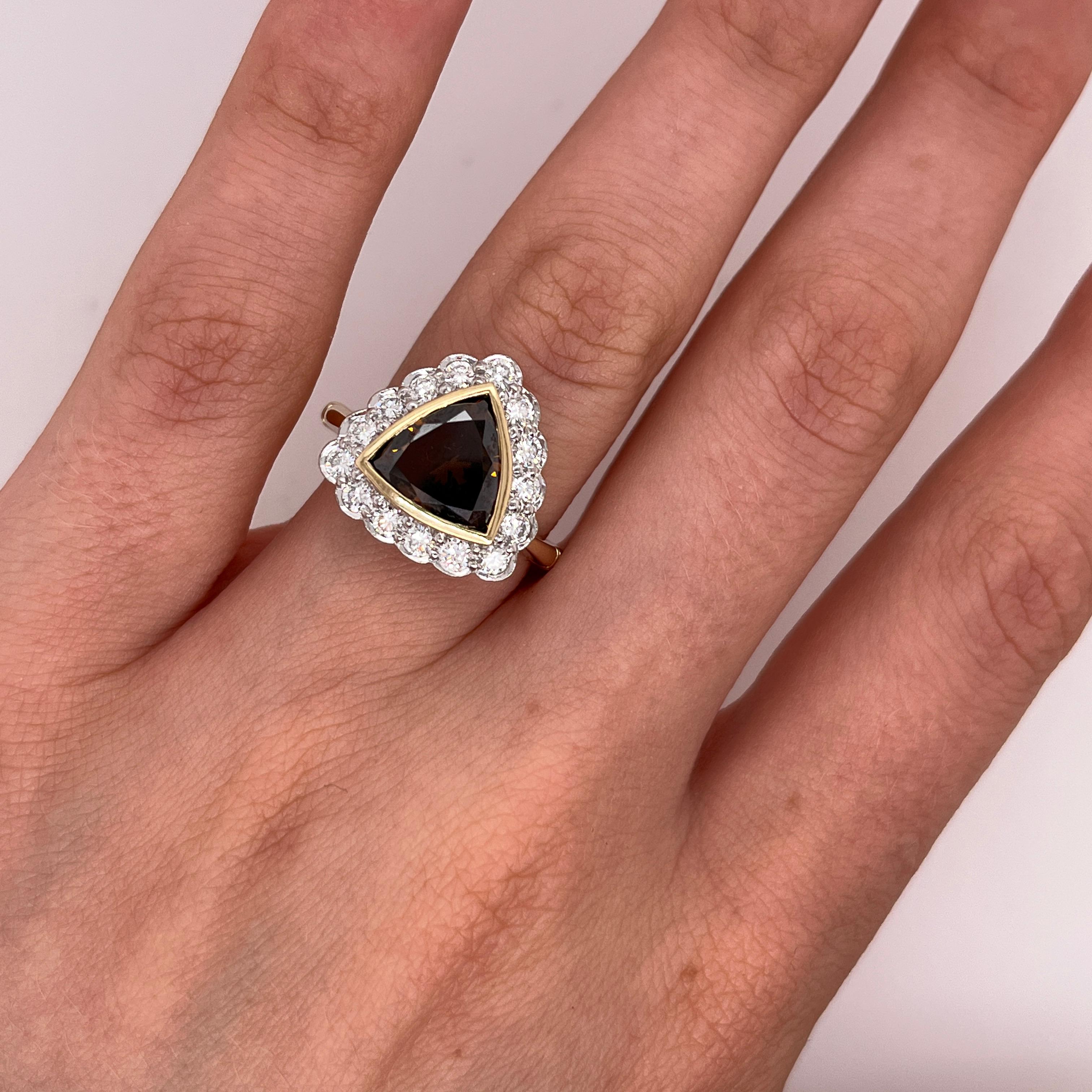 Bague en or jaune et blanc 18ct, diamant triangulaire orange-brun et halo de 1,70ct.
Un diamant naturel de taille triangulaire de 1,70ct de couleur orange-brune. 
occupe une place centrale dans ce design unique. 
Le diamant est encadré par un halo