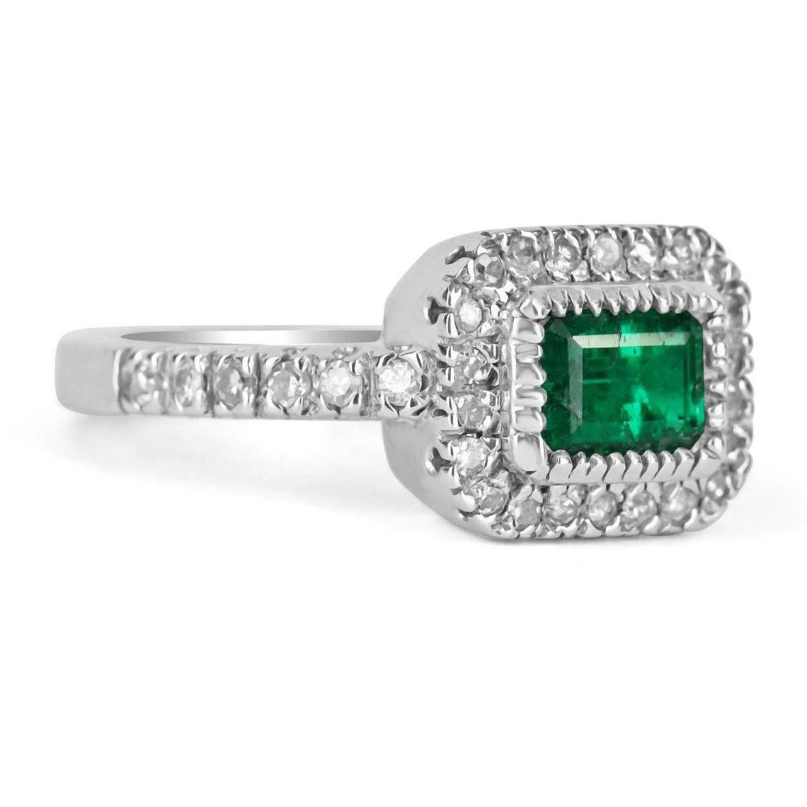 This is an outstanding, top quality, dark green emerald cut Colombian Emerald and diamond ring. Created in 14k glistening white gold the enticing 1.15ct dark green emerald is side set and is surrounded by numerous 0.55pts diamonds that also follow