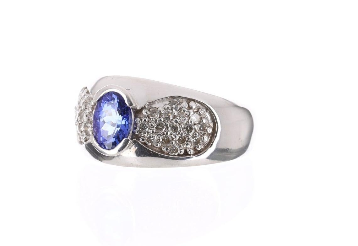 Displayed is a stunning Tanzanite & Diamond pave ring band that is full of life and sparkle from all sides! 30 fully faceted round cut diamonds are set on either side of the tanzanite. Created in solid 14 karat gold, this ring showcases a wondrous